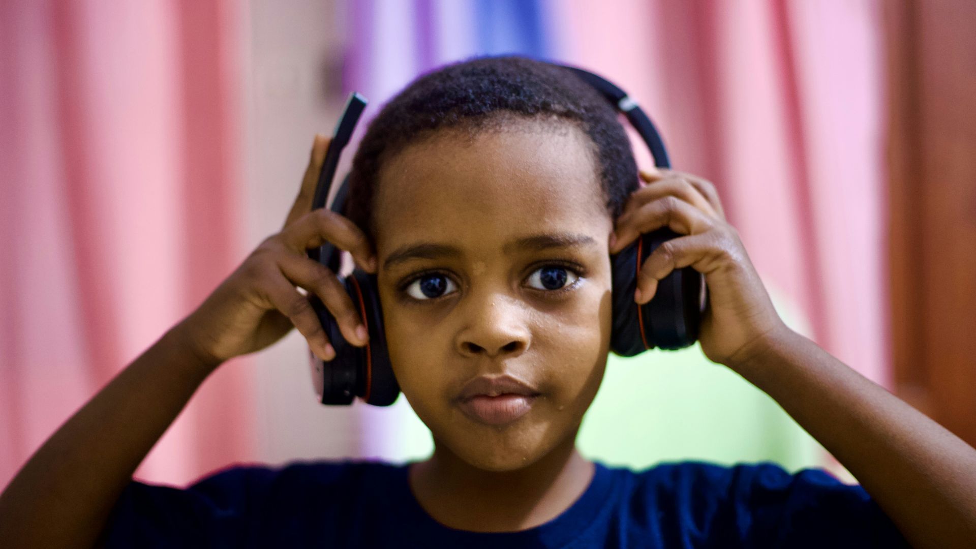 A young boy listening to headphones in a room