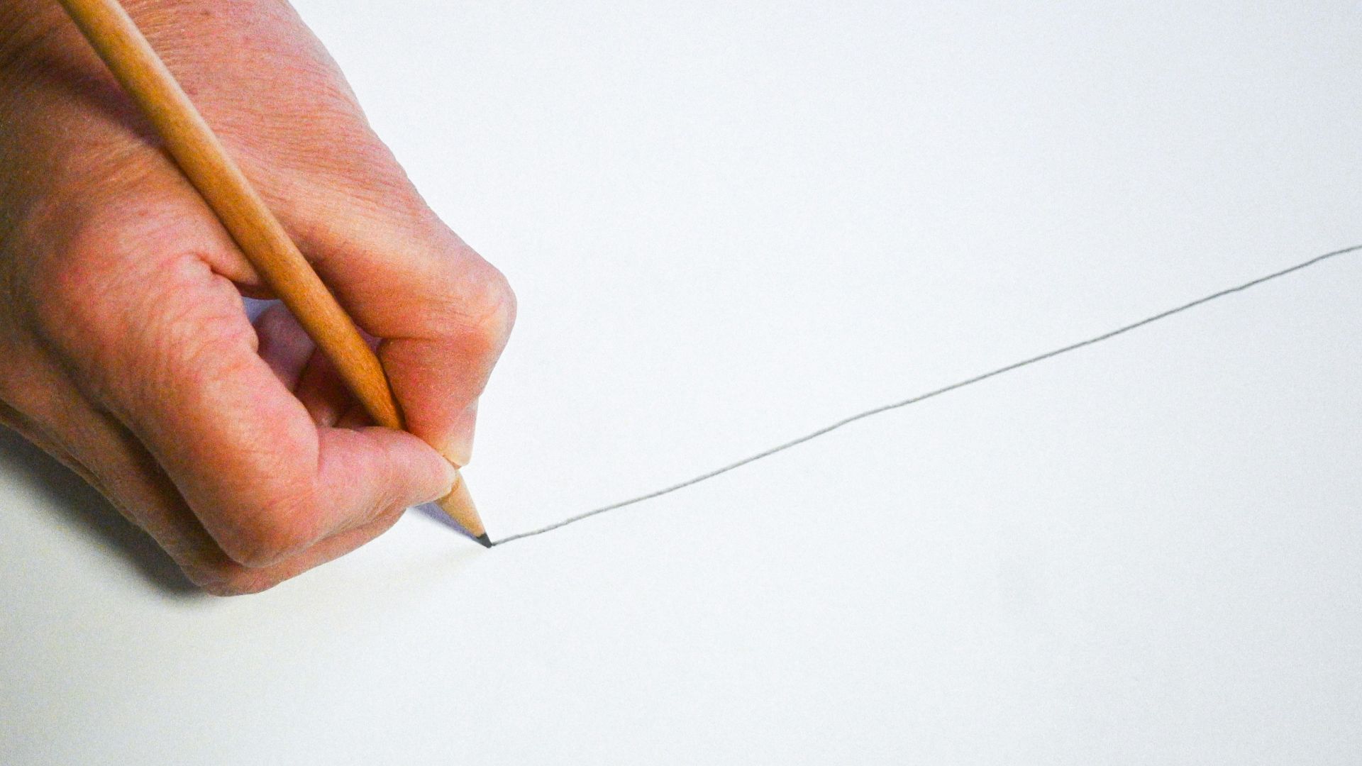 A person holding a pencil and writing on a piece of paper