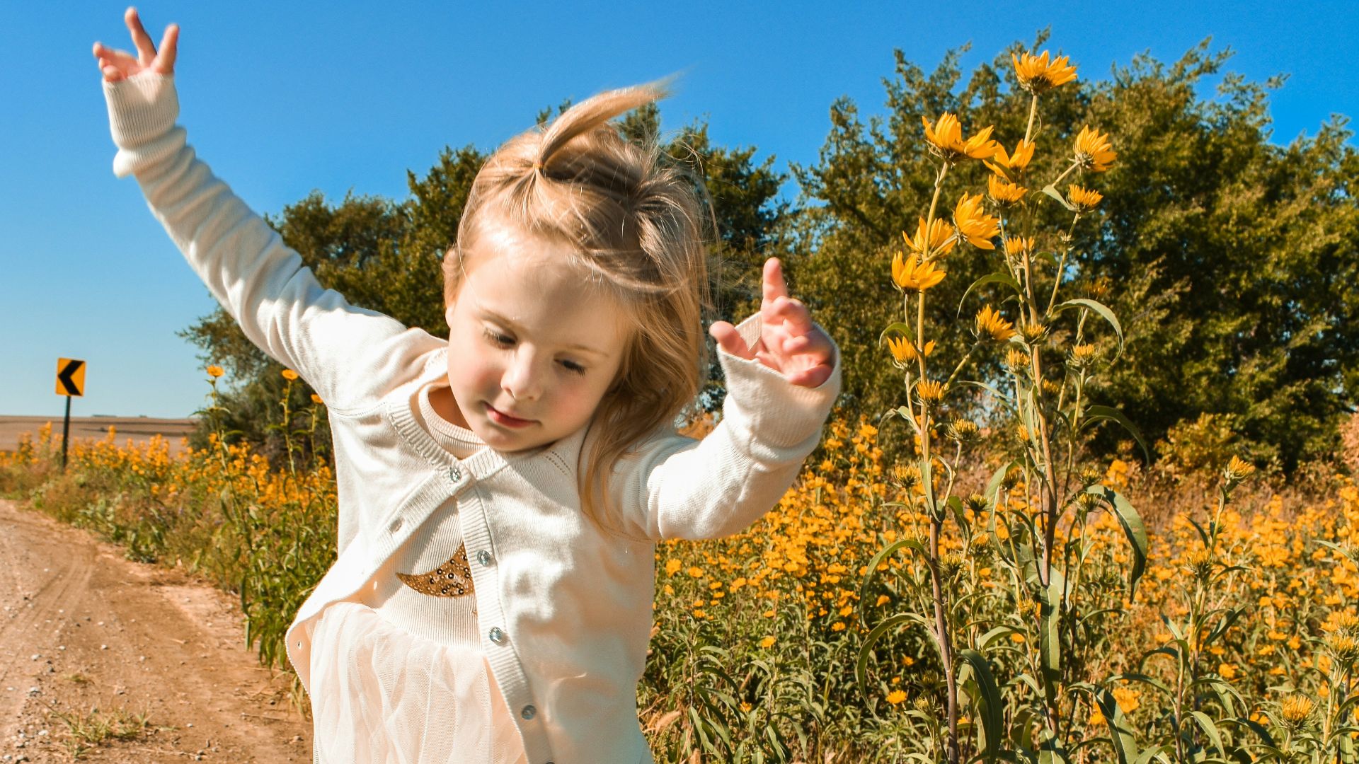 girl in white dress shirt and blue denim jeans standing on brown soil during daytime