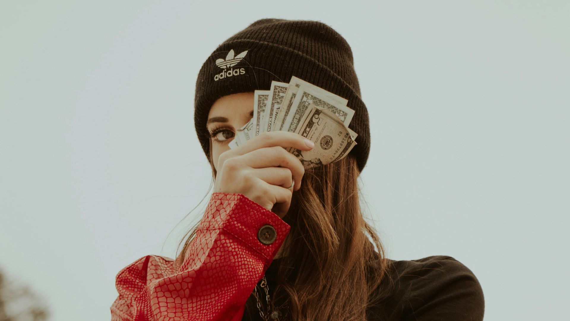 woman in black knit cap covering her face with her hand