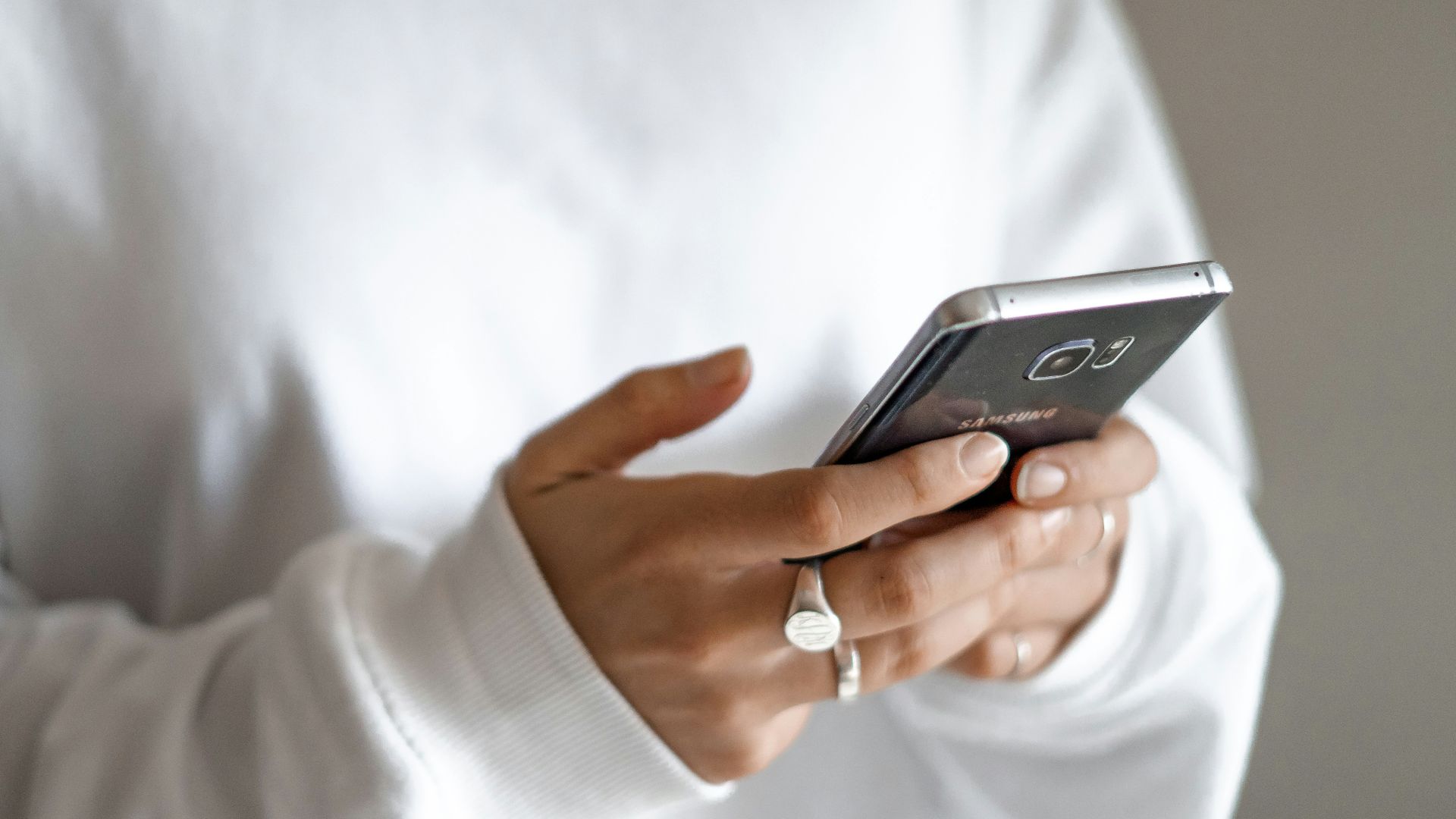 person in white long sleeve shirt holding black smartphone
