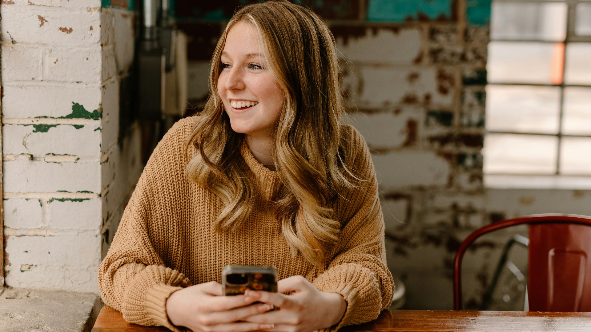 a woman sitting at a table with a cell phone