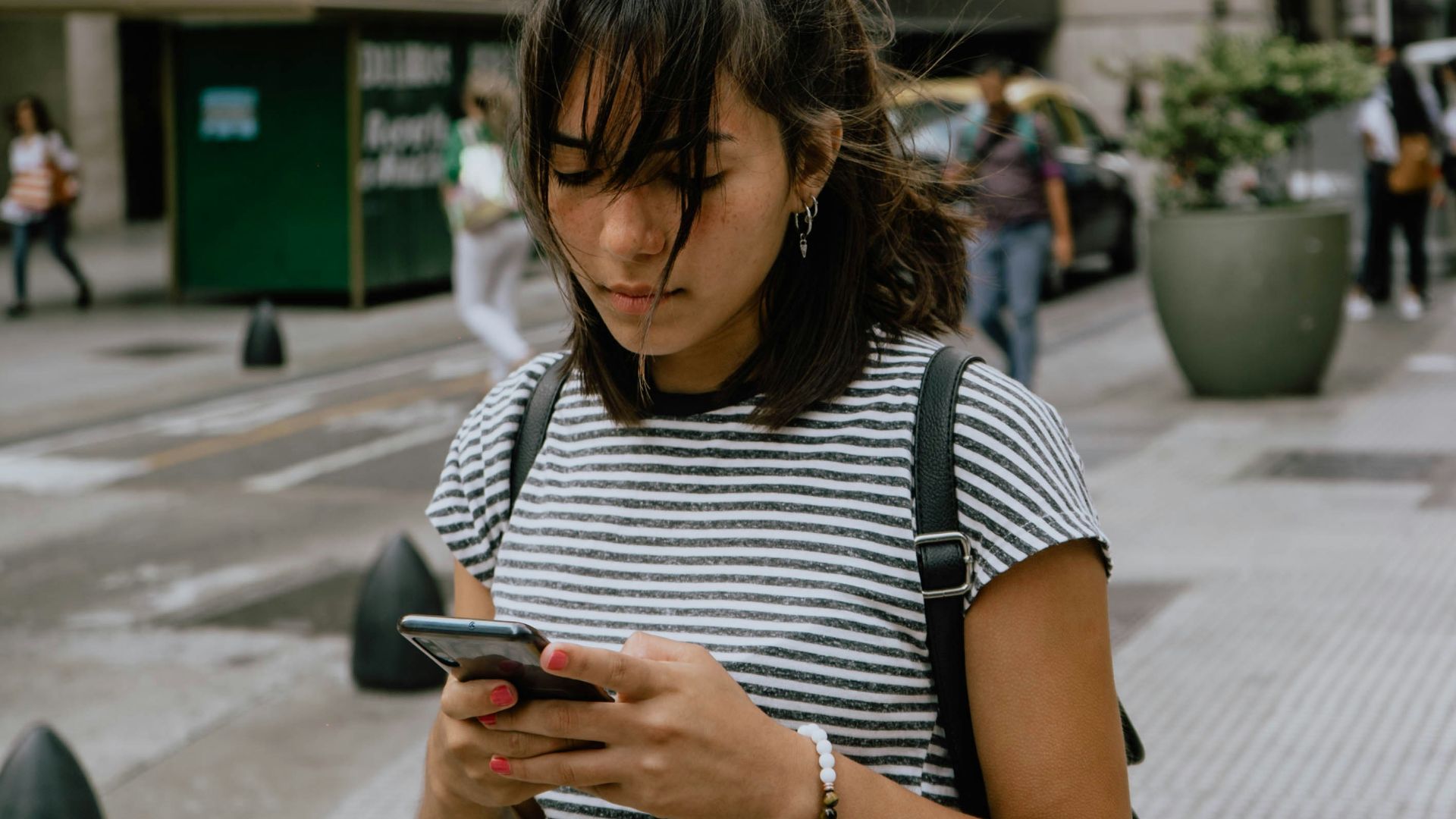 woman in black and white stripe shirt using smartphone