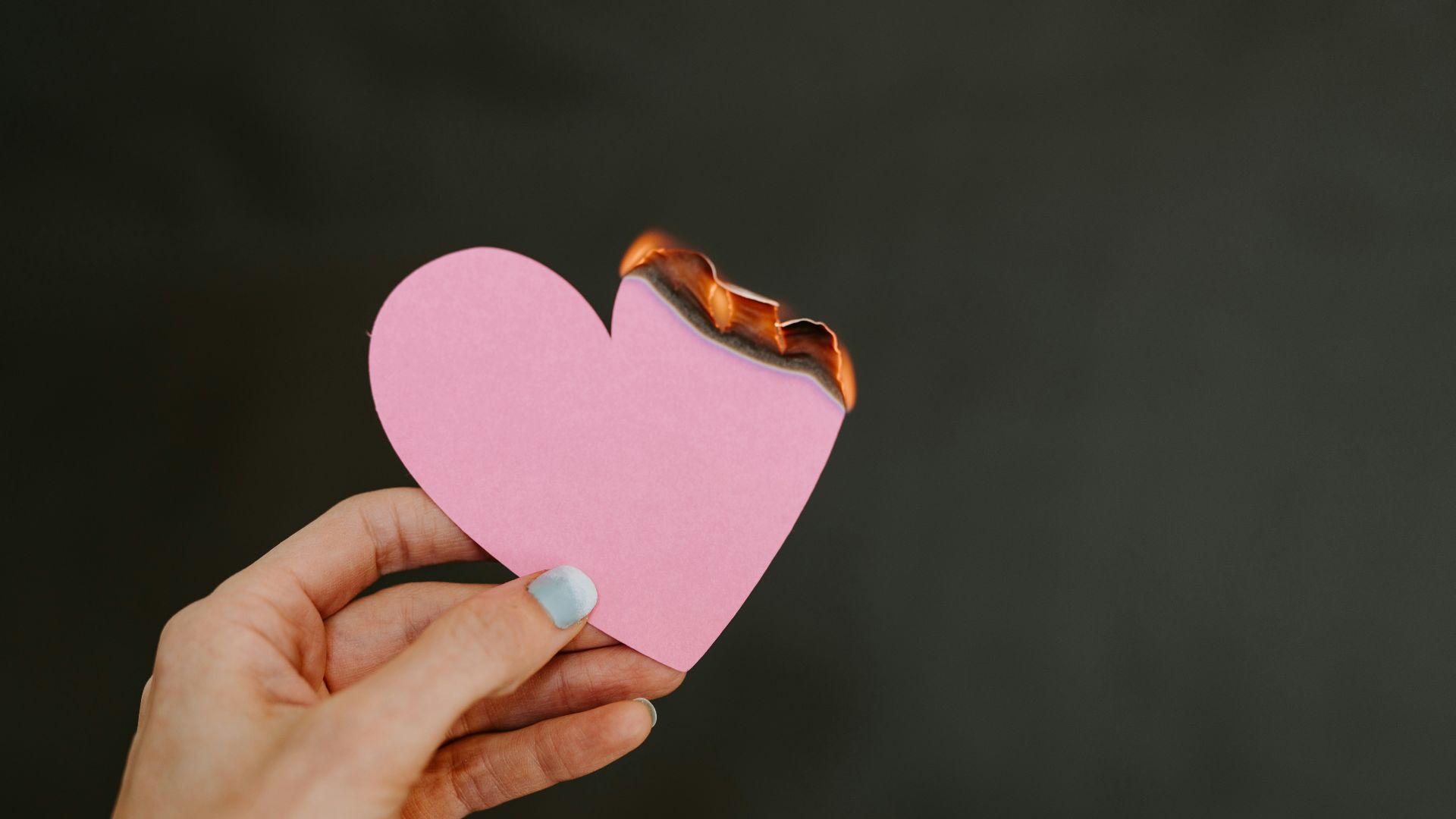 a person holding a pink heart shaped piece of paper