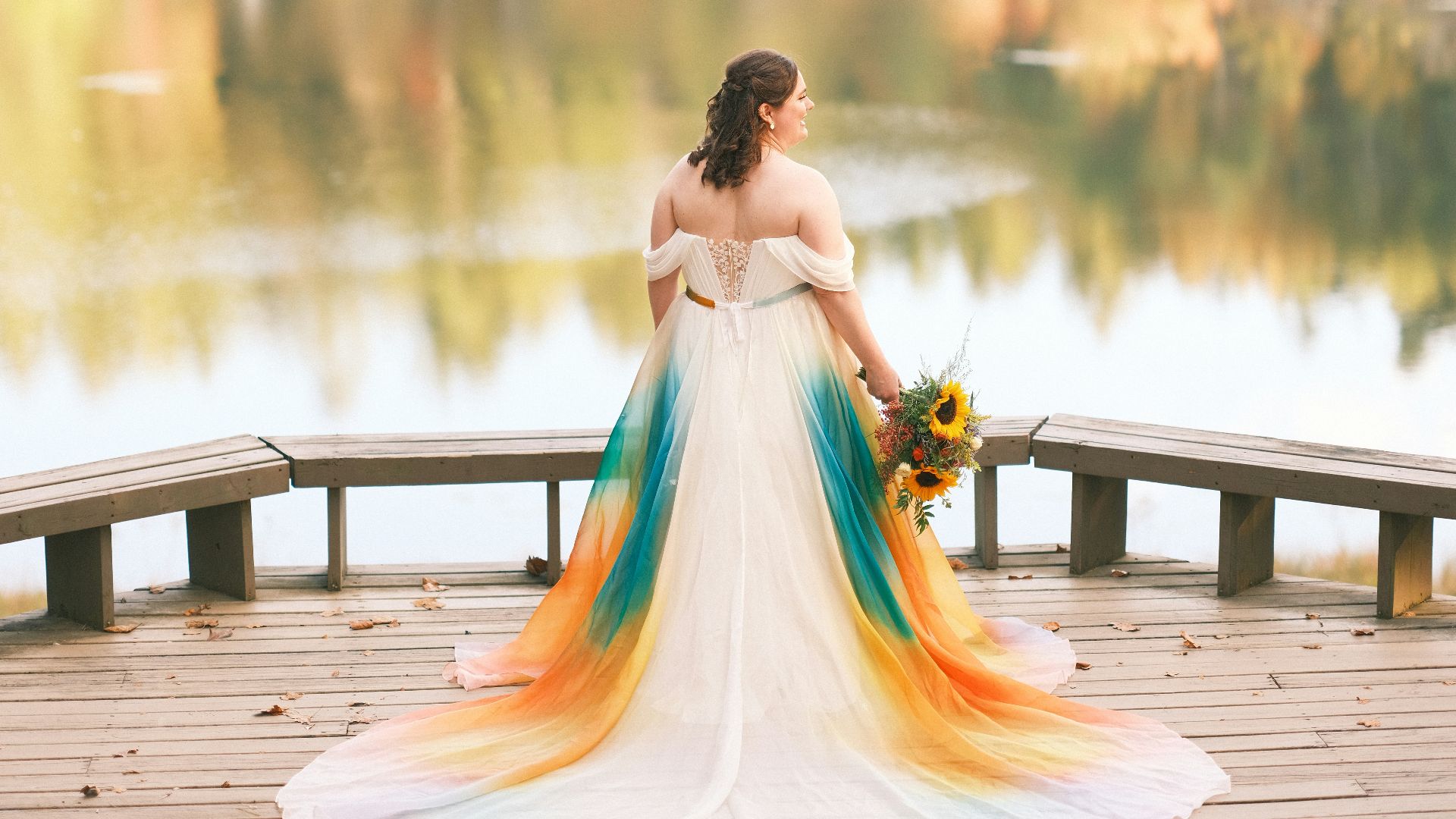a person in a dress sitting on a dock by a lake