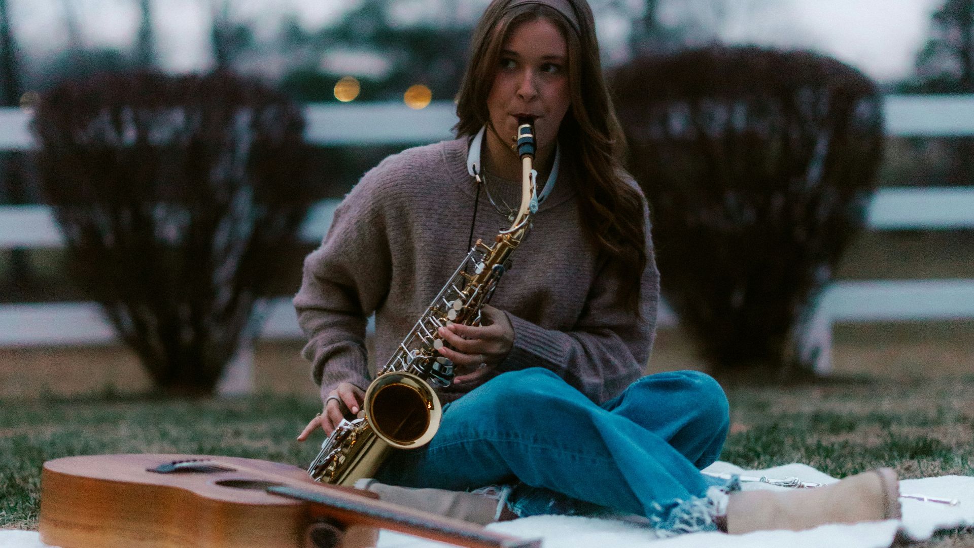 Woman playing saxophone with guitars on blanket