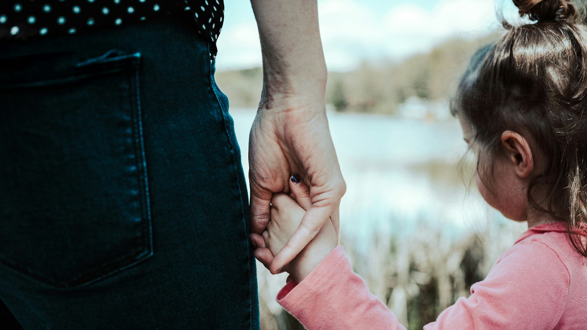 girl in pink jacket holding her hair