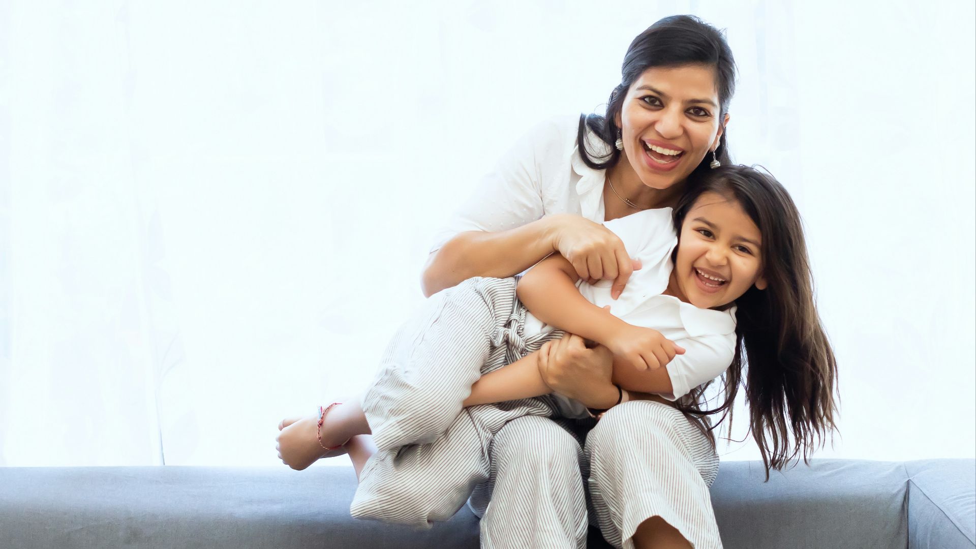 2 women sitting on gray couch