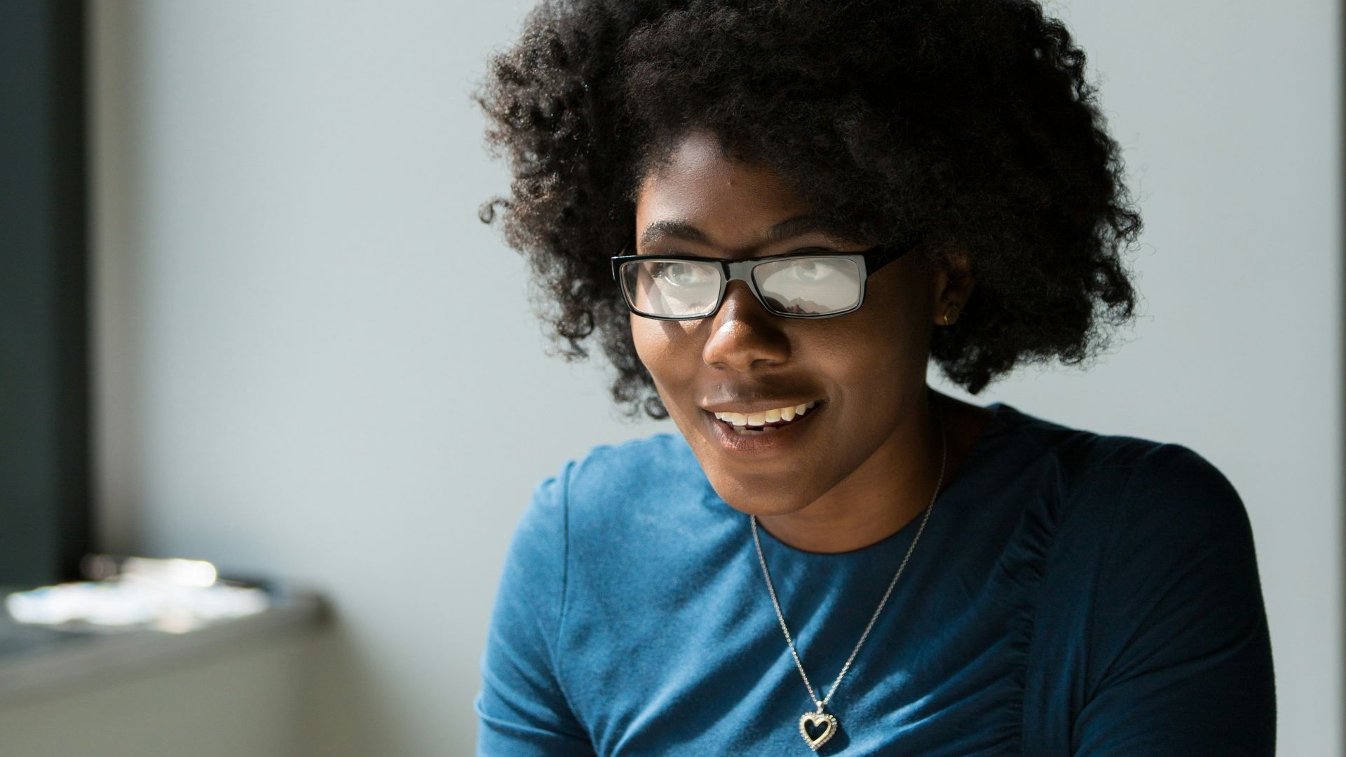 smiling woman wearing blue shirt sitting beside table