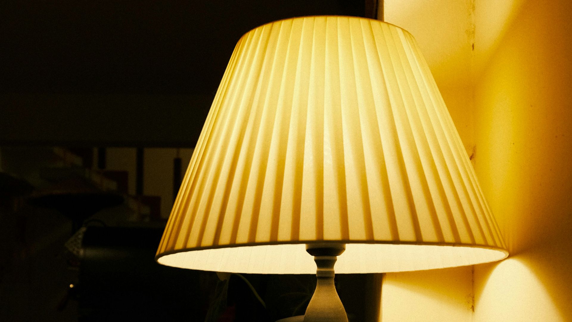 A lit lamp stands beside a stack of books.