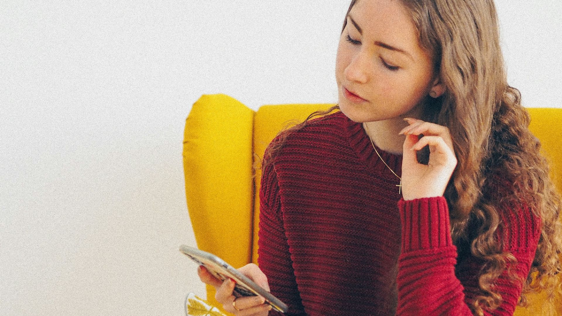 woman in red sweater and blue denim jeans sitting on yellow sofa chair