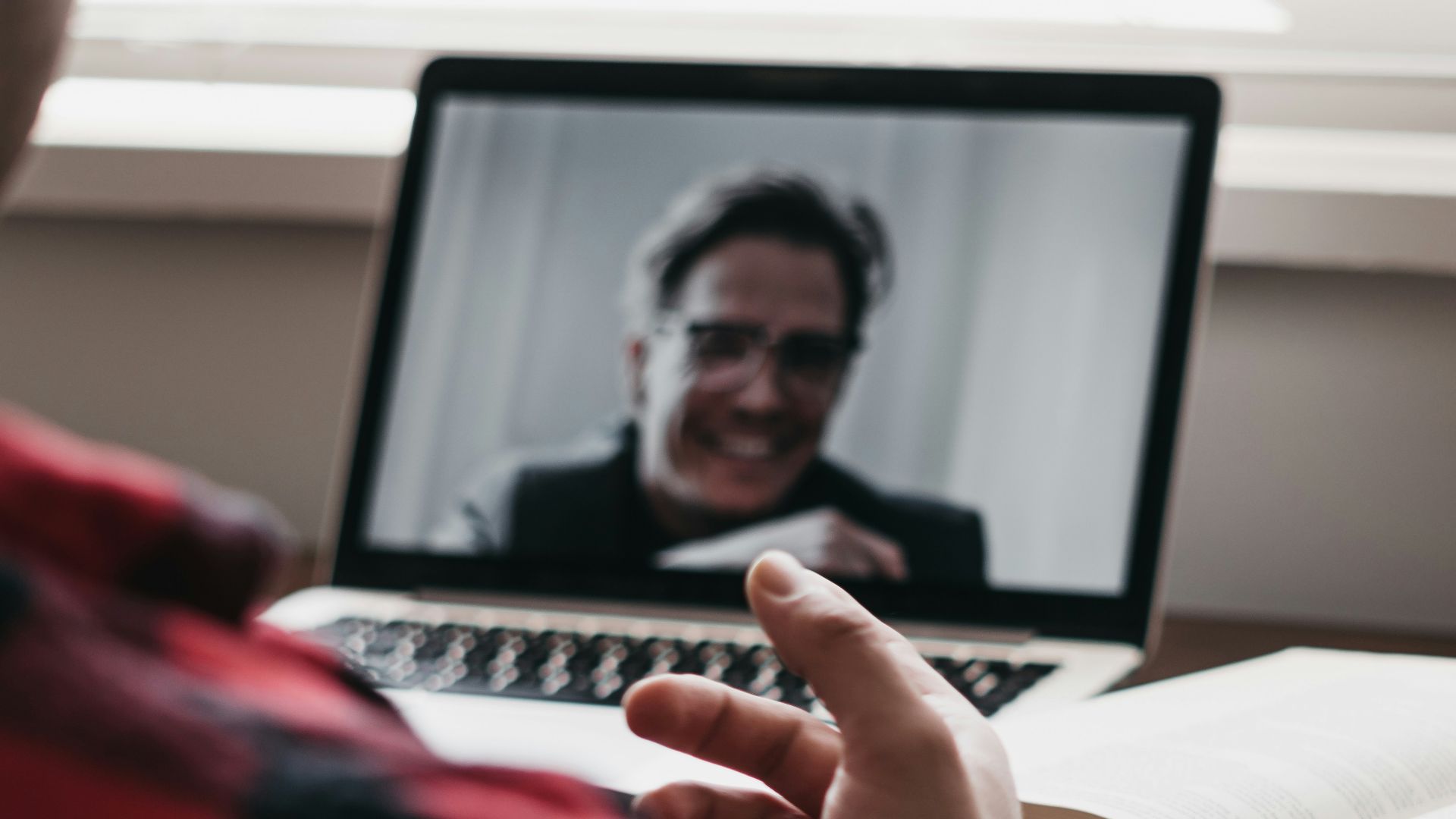 person in red and black plaid long sleeve shirt using black laptop computer