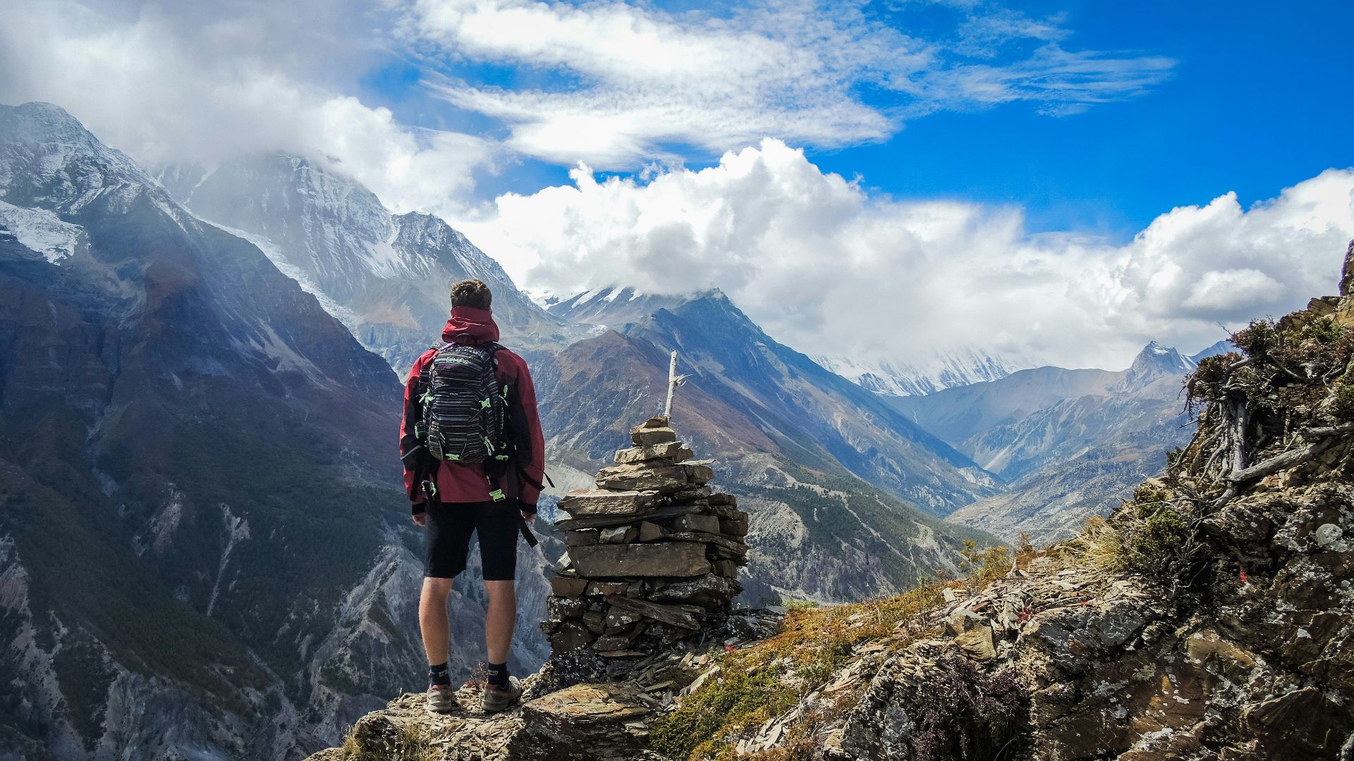 man standing on top of mountain beside cairn stones