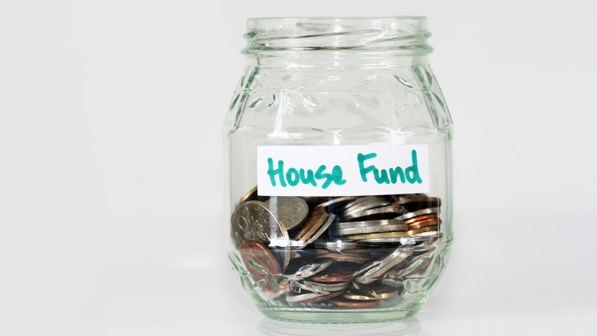 coins in clear glass jar with house fund sign