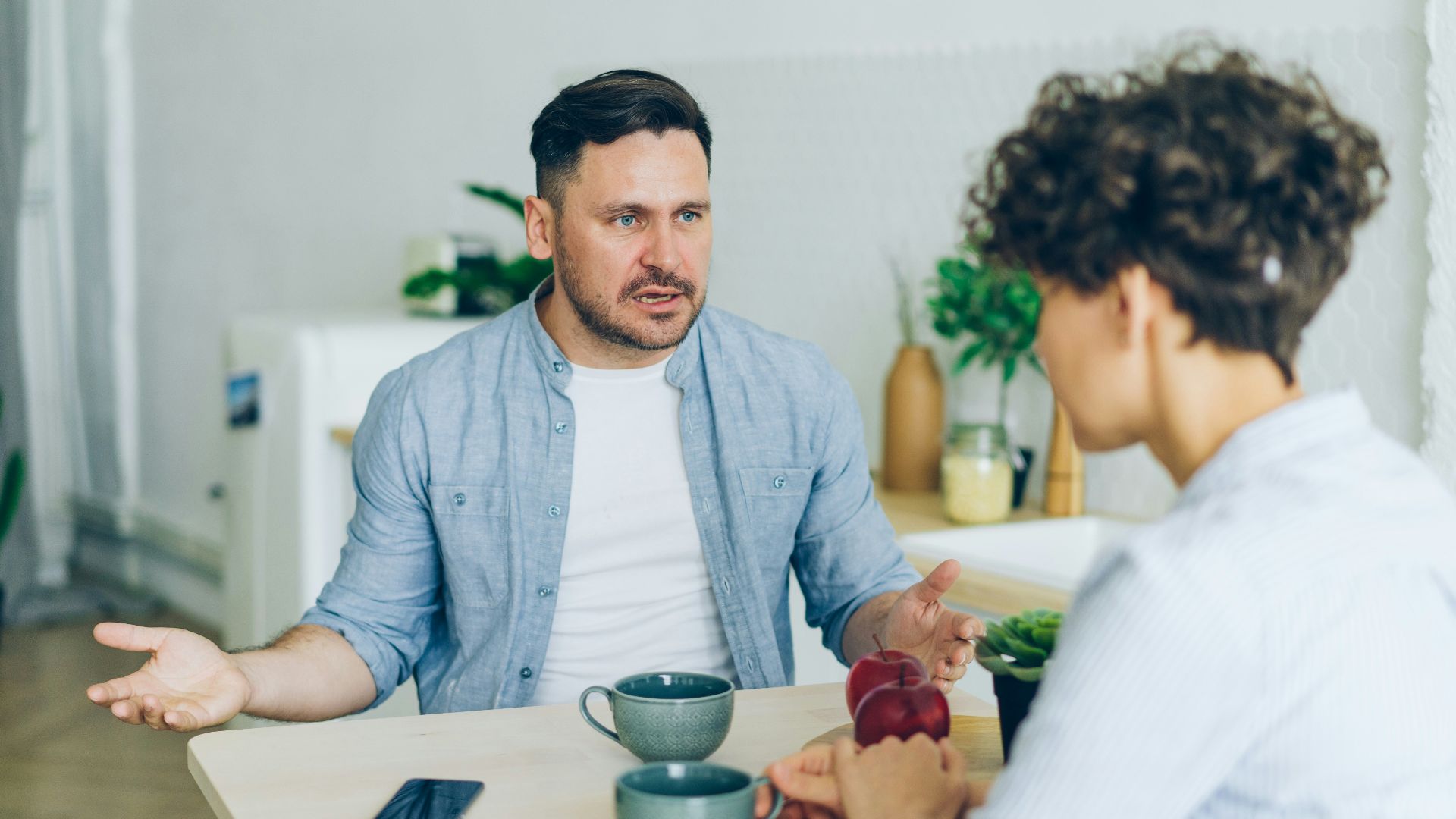 a man sitting at a table talking to a woman