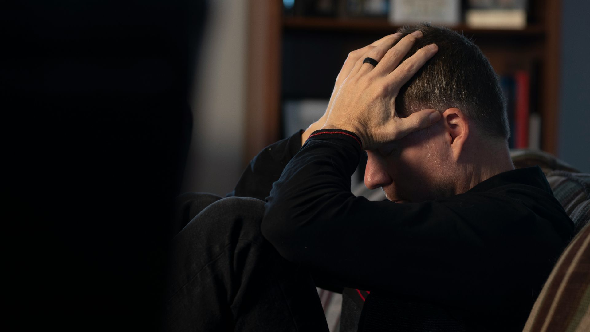 a man sitting on a couch holding his head in his hands
