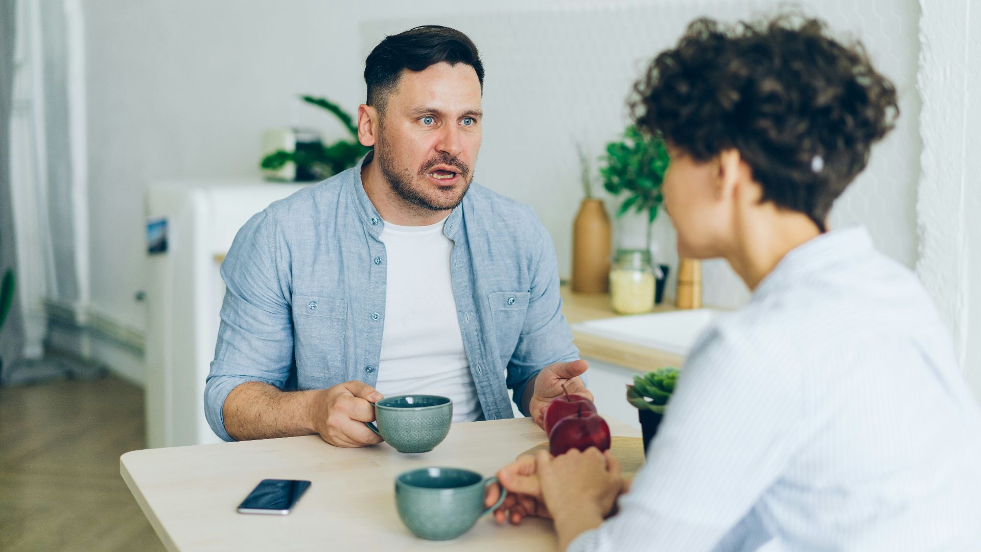a man sitting at a table talking to a woman