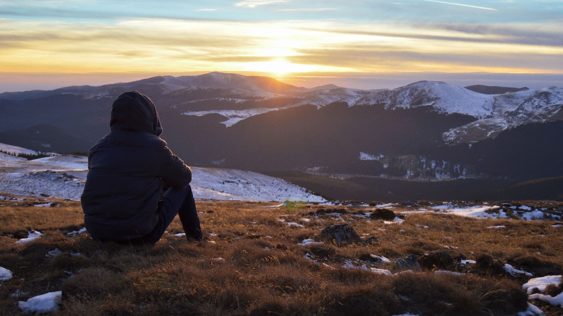 person standing on grass facing on mountain