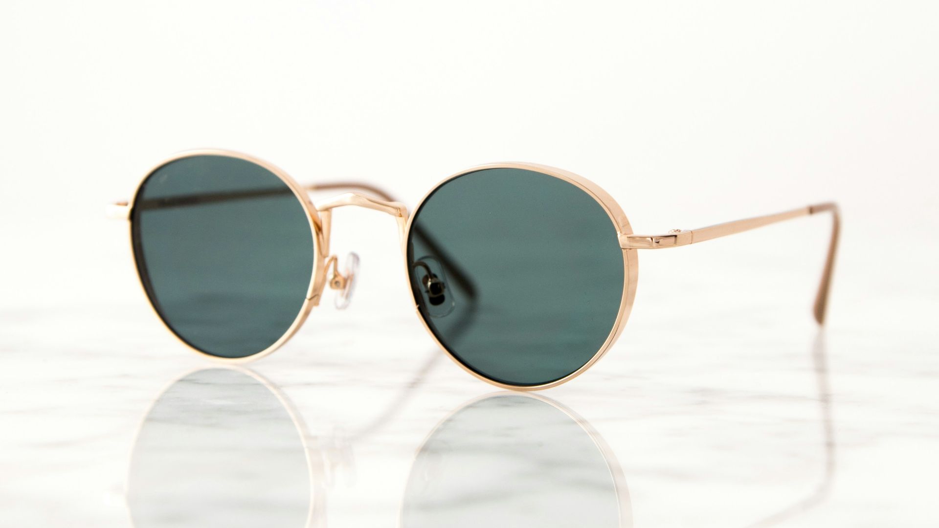 gold-colored framed hippie sunglasses on white surface