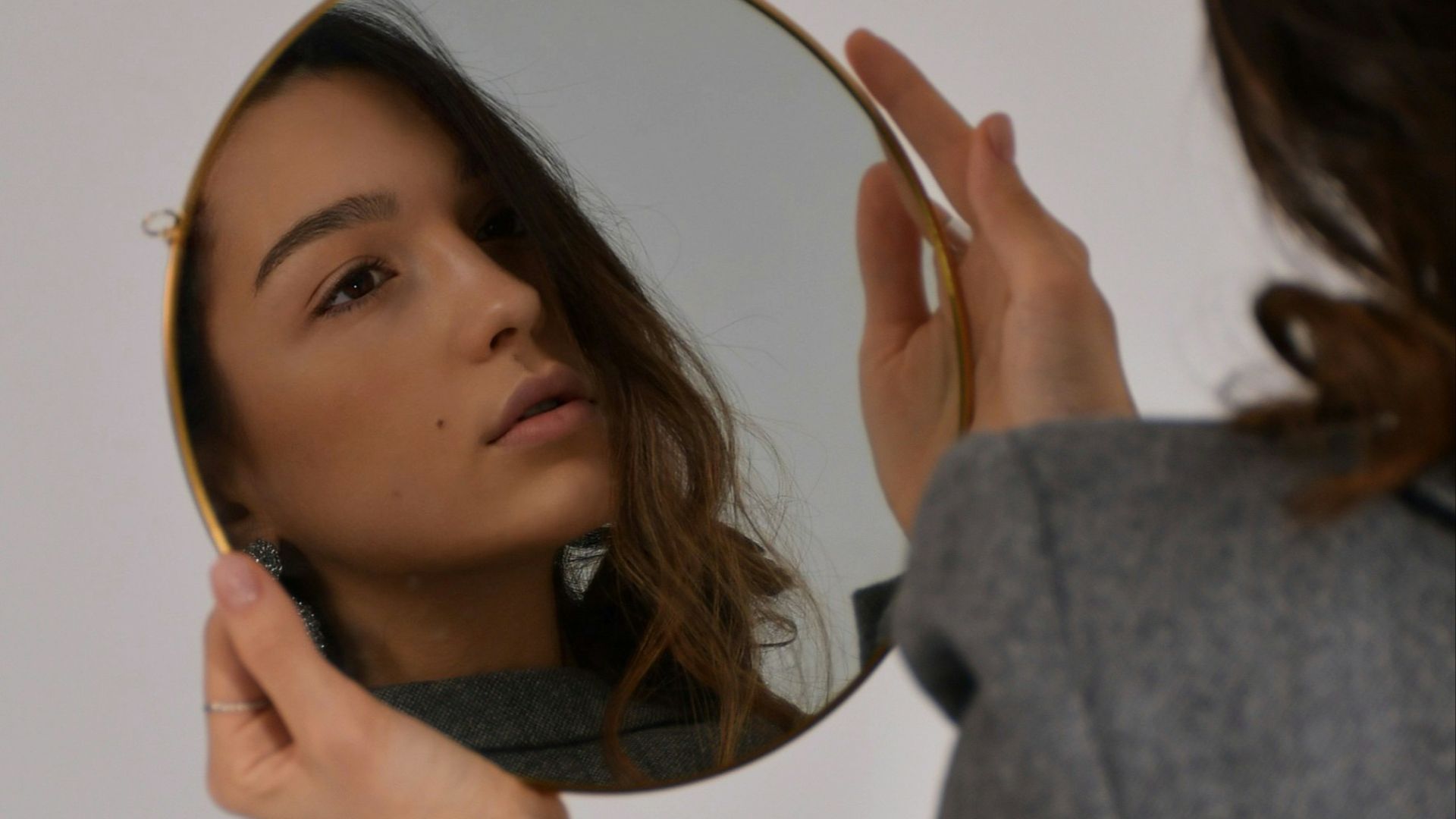 woman in gray long sleeve shirt holding her head