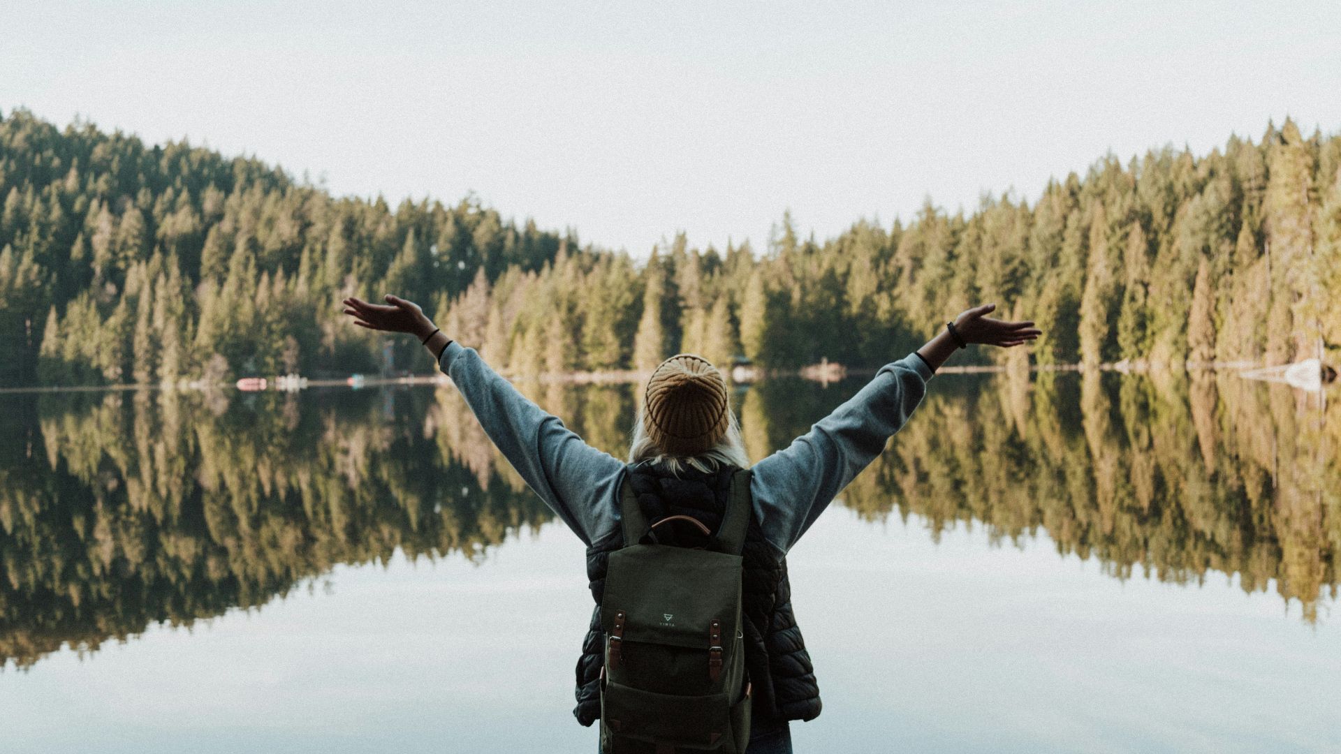 woman open her arms facing calm body of water