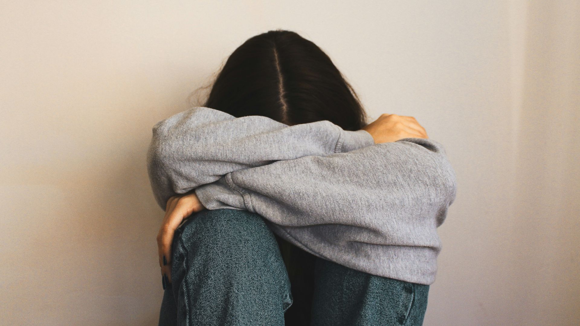 a woman sitting on the floor with her arms wrapped around her head