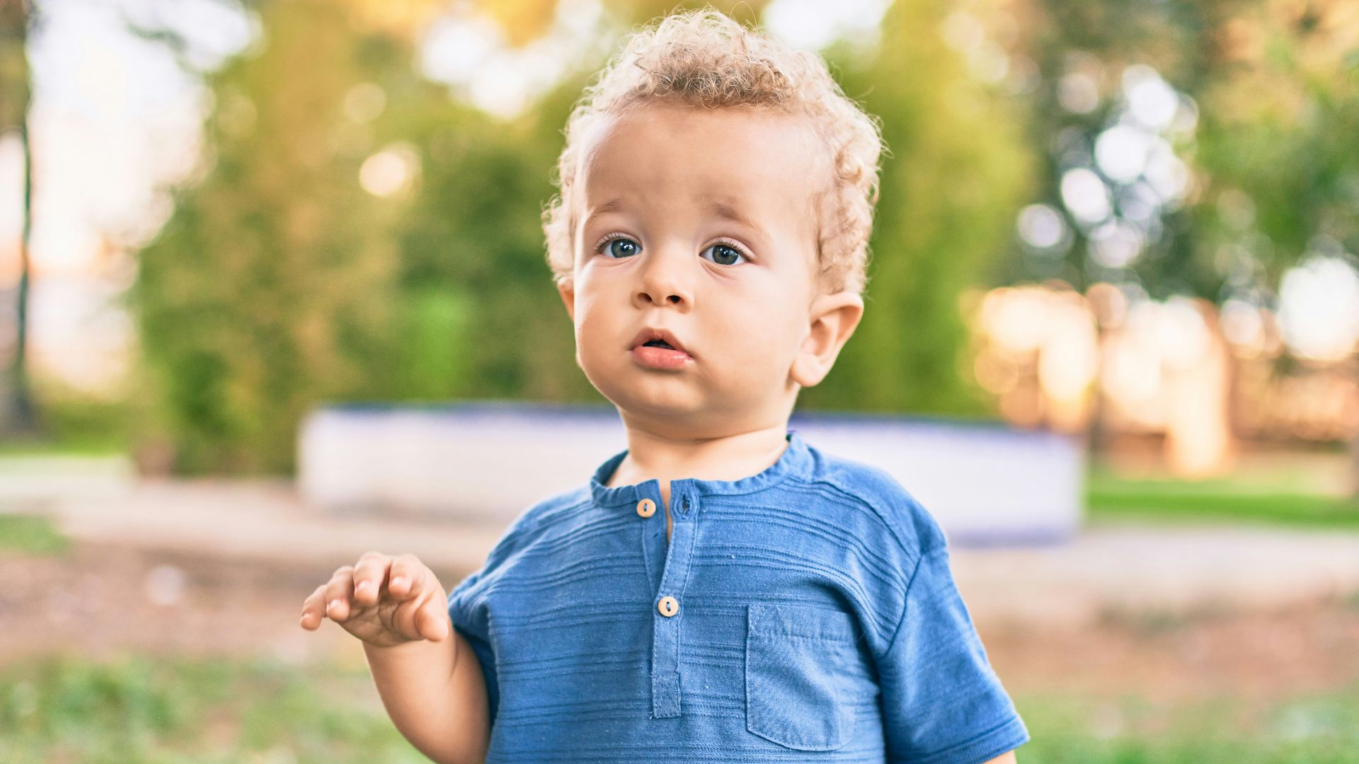 boy in blue polo shirt and blue denim shorts standing on green grass field during daytime