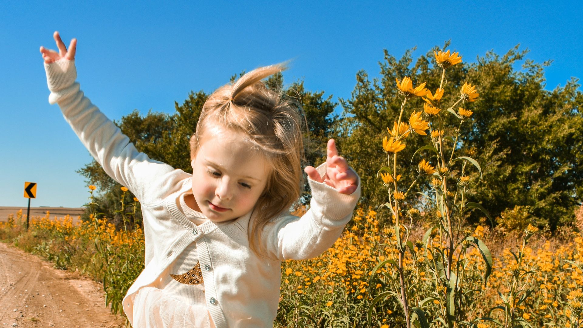 girl in white dress shirt and blue denim jeans standing on brown soil during daytime