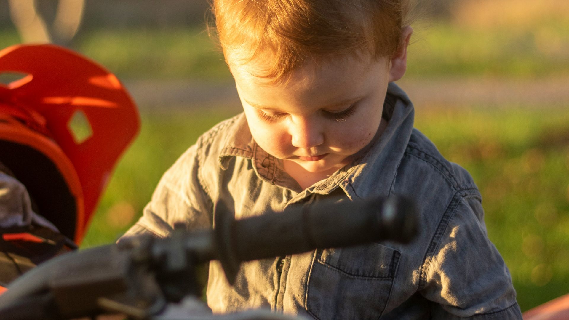 boy in blue button up shirt riding on red motorcycle during daytime