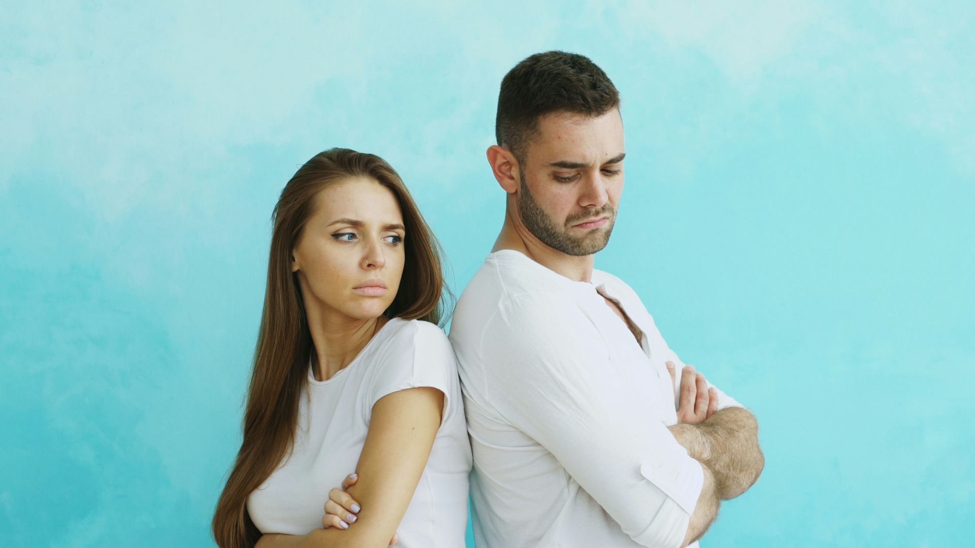 Couple standing back to back with arms crossed