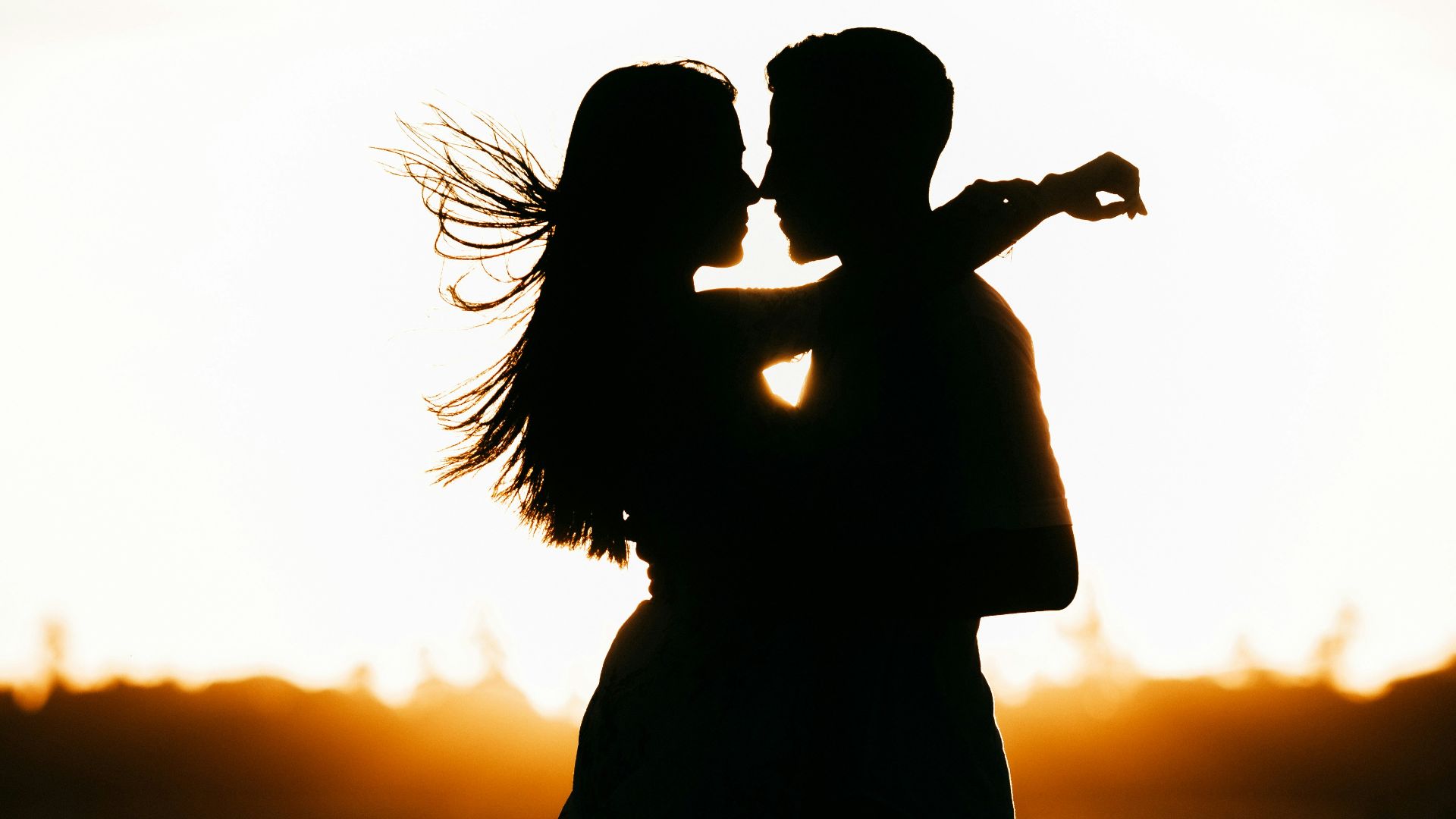 silhouette of woman standing on beach during sunset