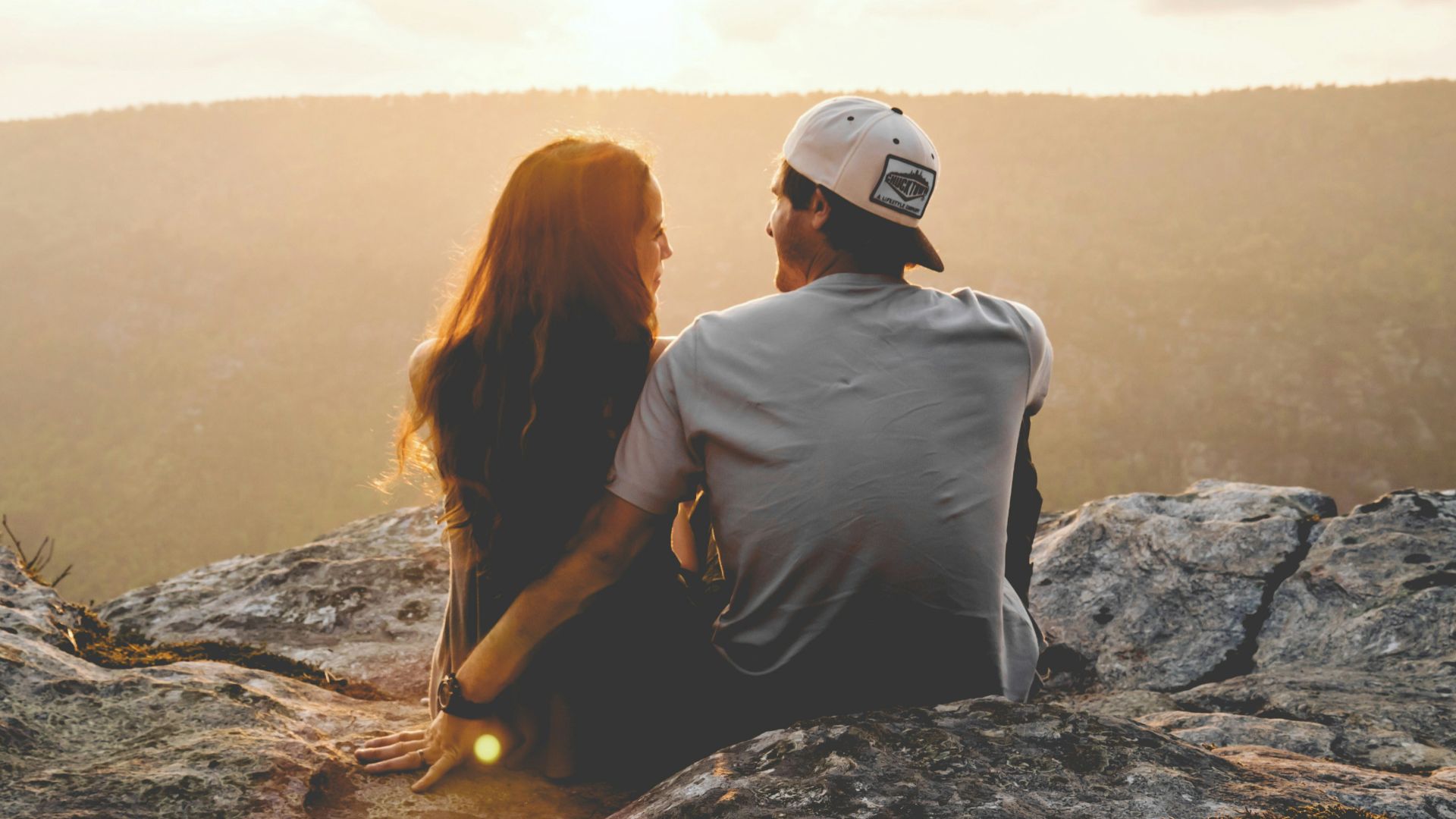 man and woman sitting on rock during daytime