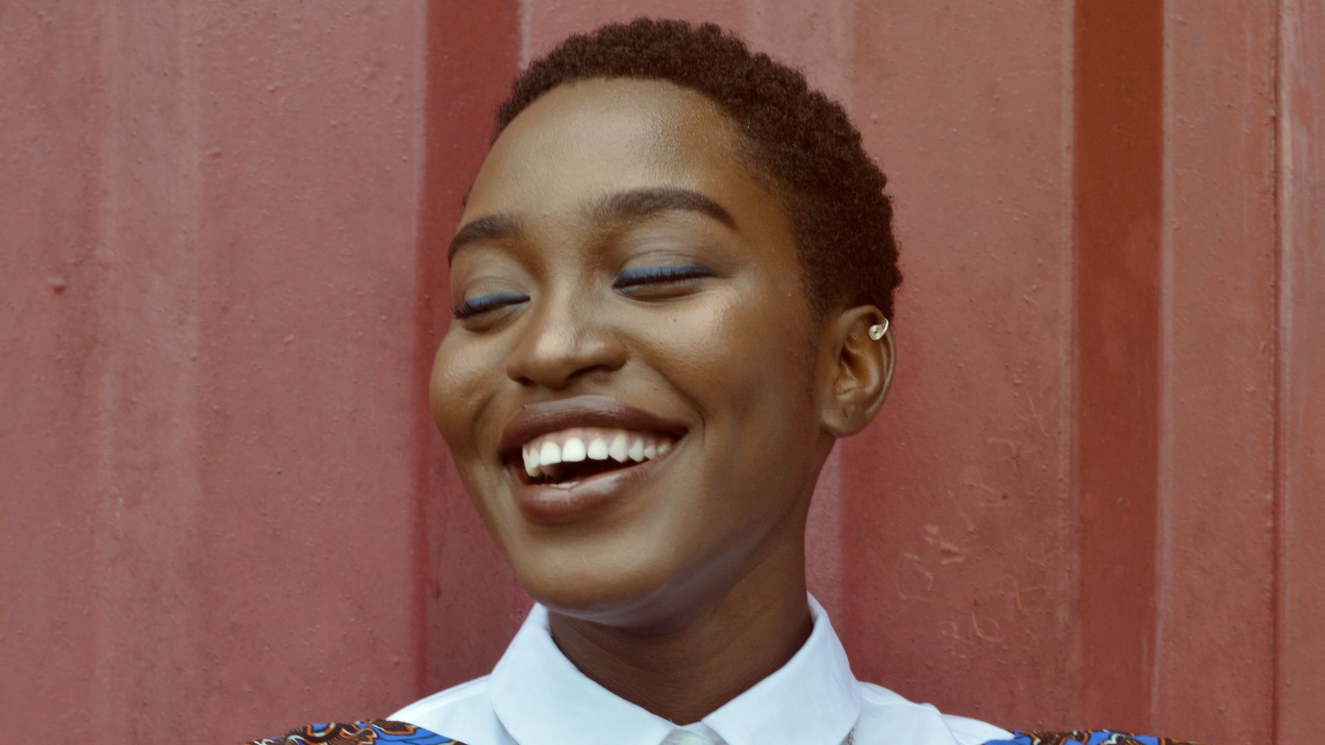 woman smiling beside red wall
