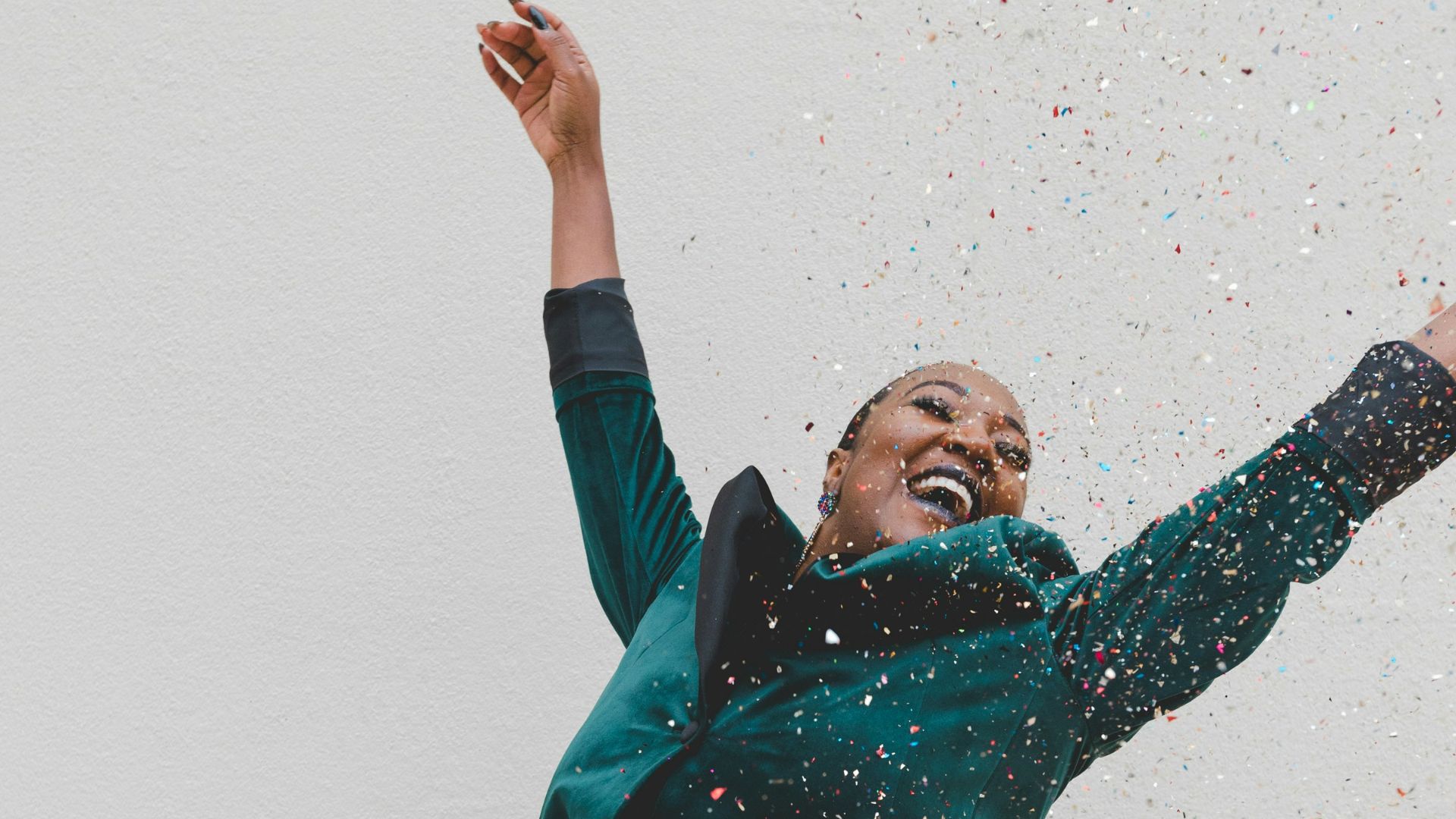 woman in green jacket raising her hands