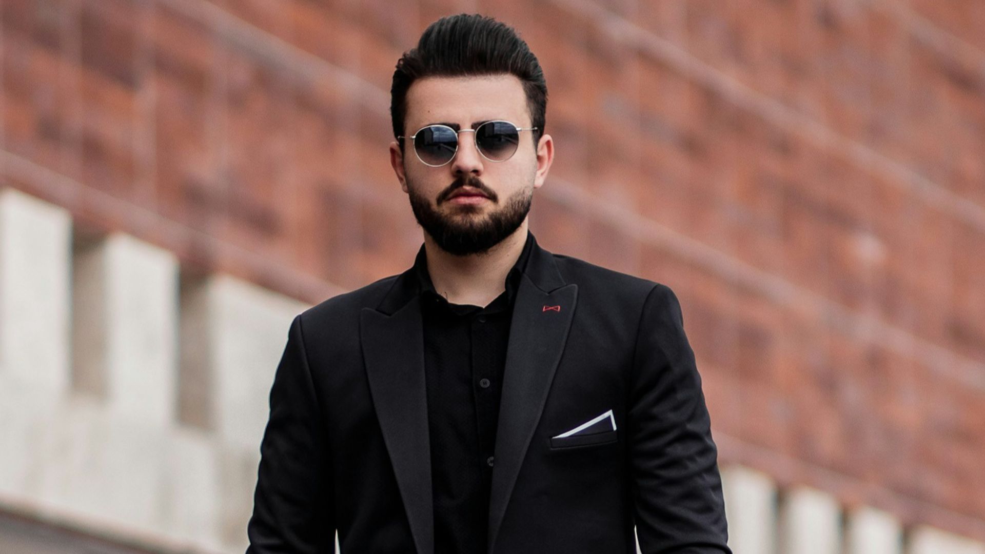 man in black suit jacket and black pants standing on gray concrete floor during daytime