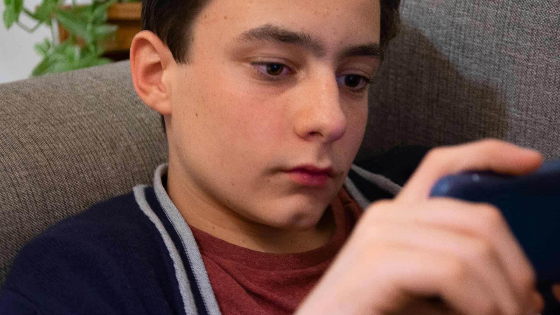 a young man sitting in a chair looking at a cell phone