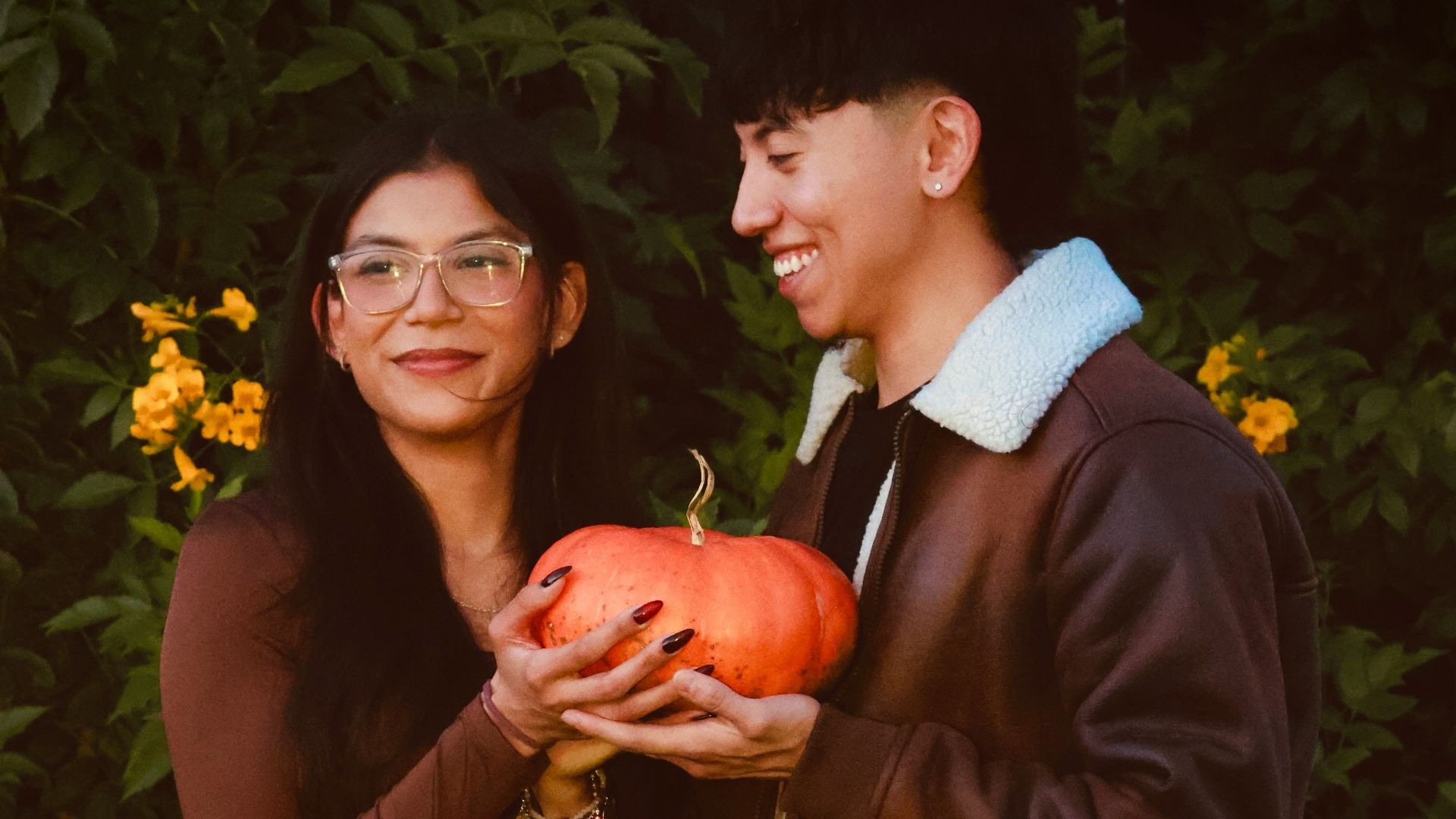 Couple holding a pumpkin with yellow flowers