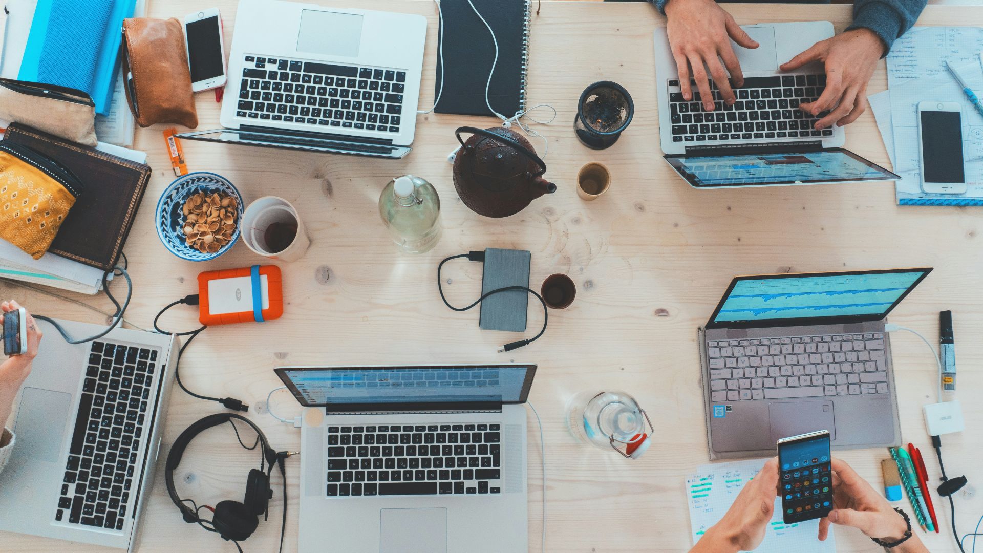 people sitting down near table with assorted laptop computers