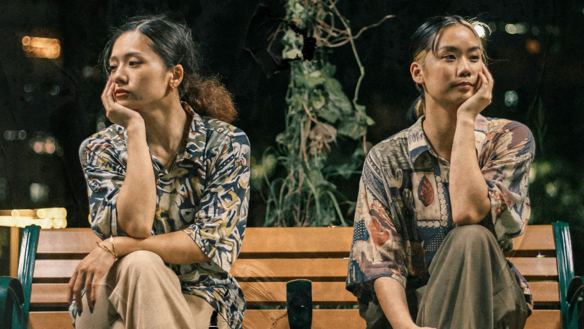 2 women sitting on brown wooden bench