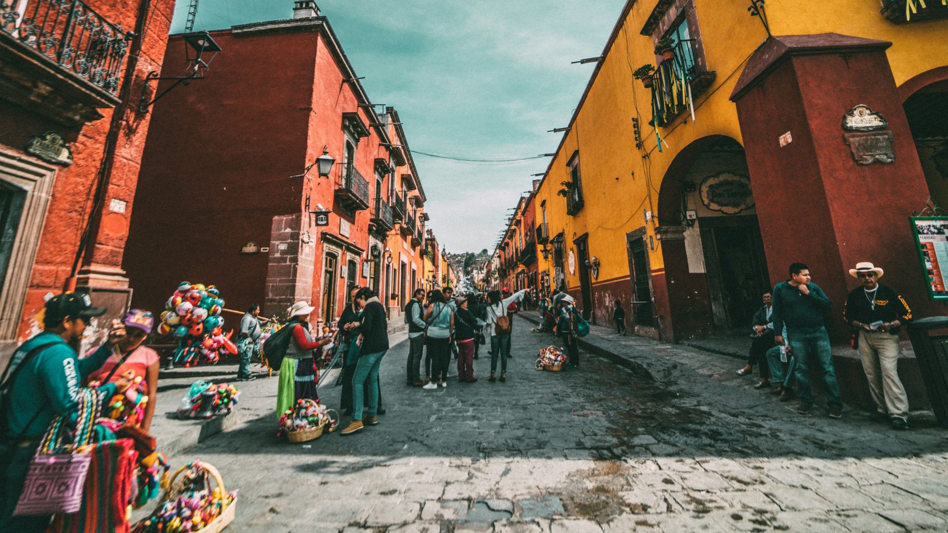 people standing on corner road near concrete buildings during daytime