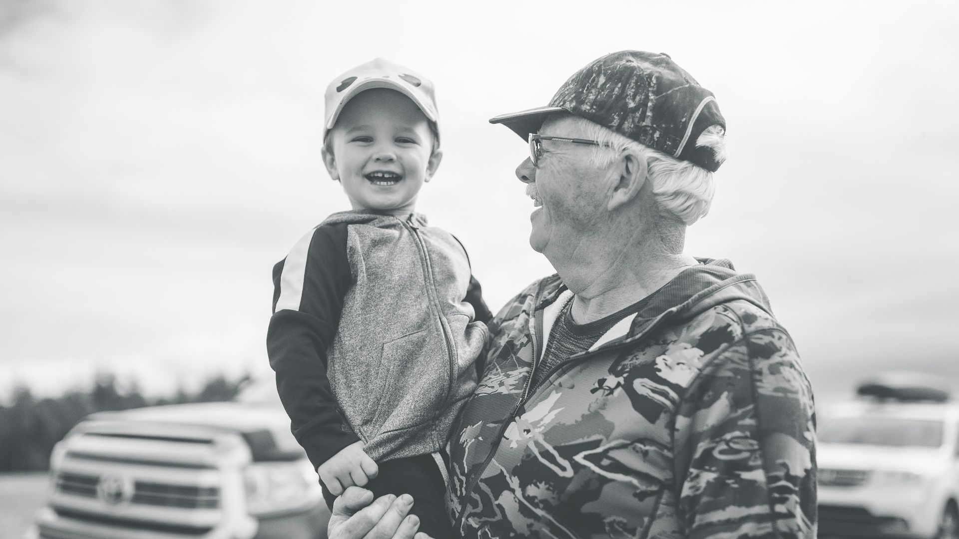 grayscale photo of boy in camouflage jacket and cap
