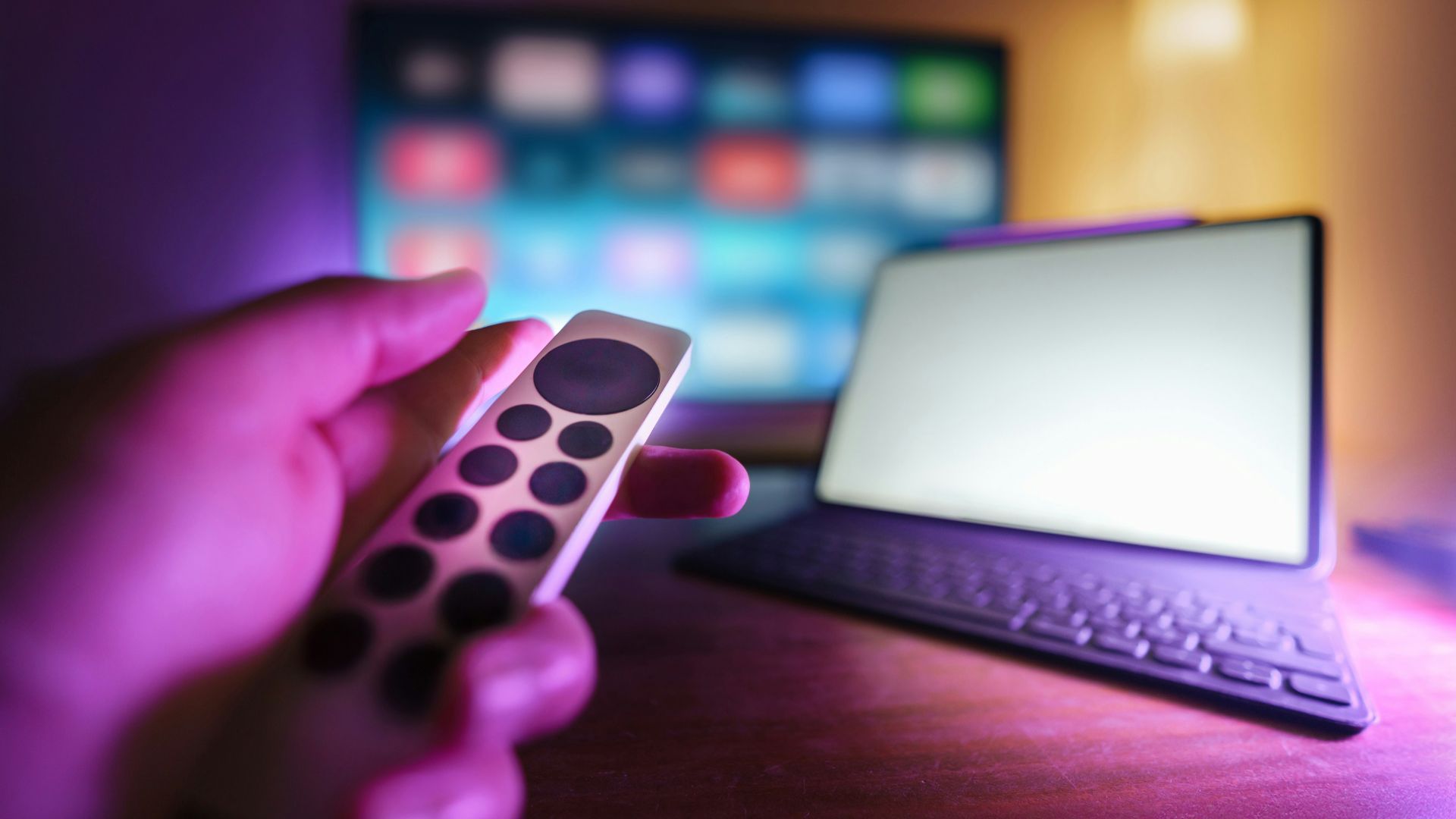 A person holding a remote control in front of a laptop