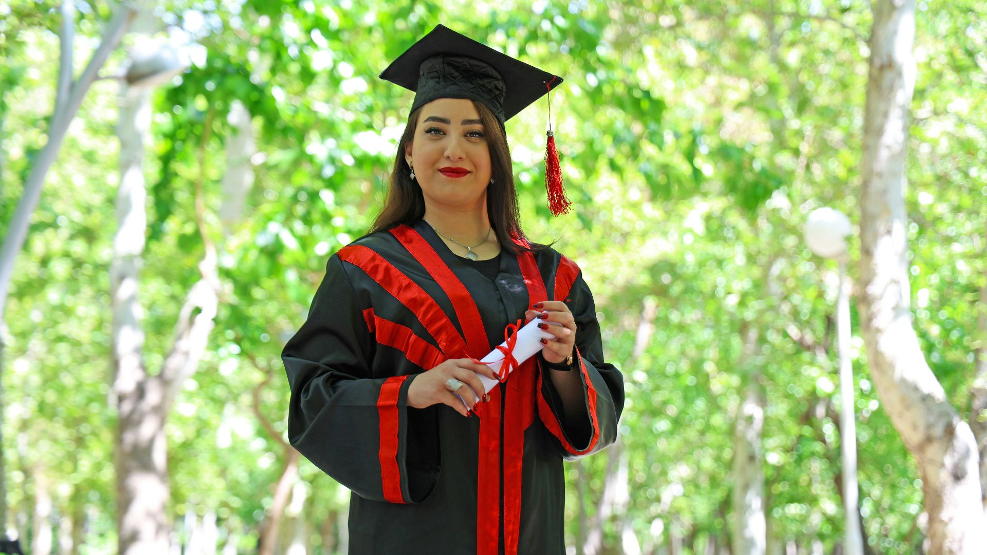 A woman in graduation gown holding a diploma