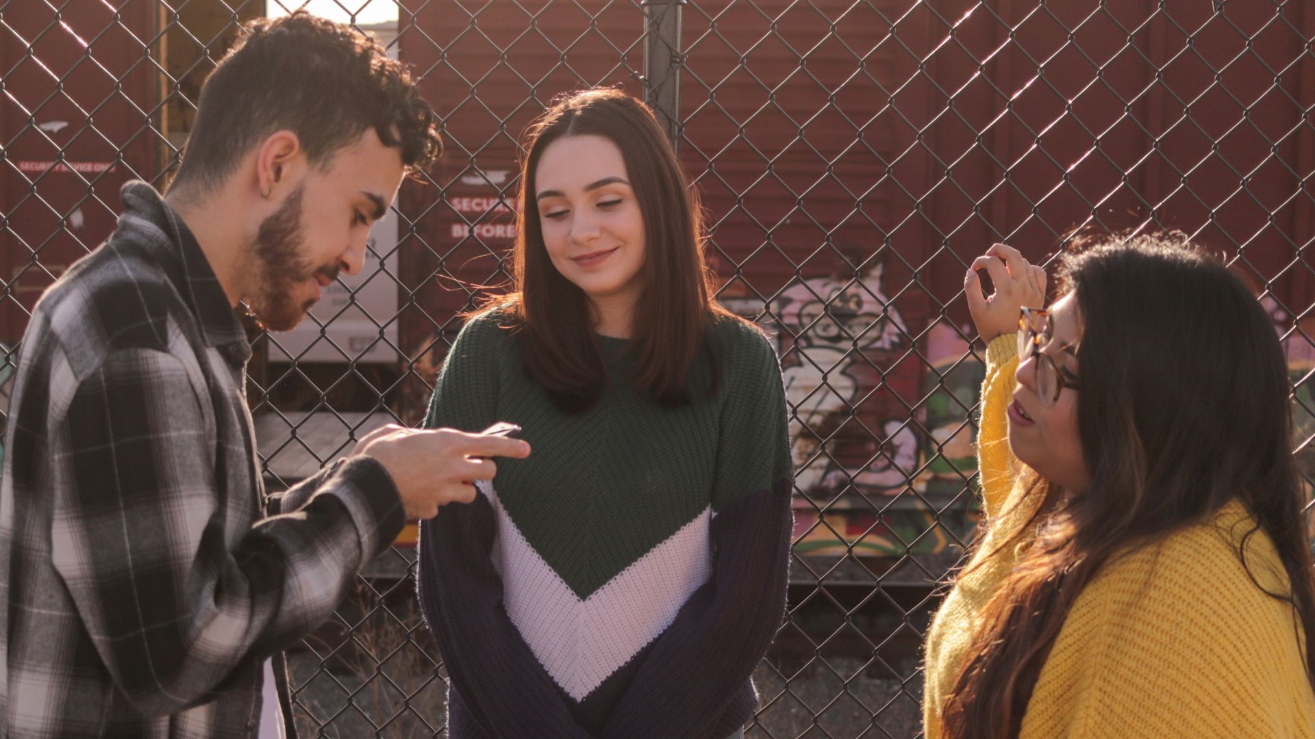 two women and one man standing near fence