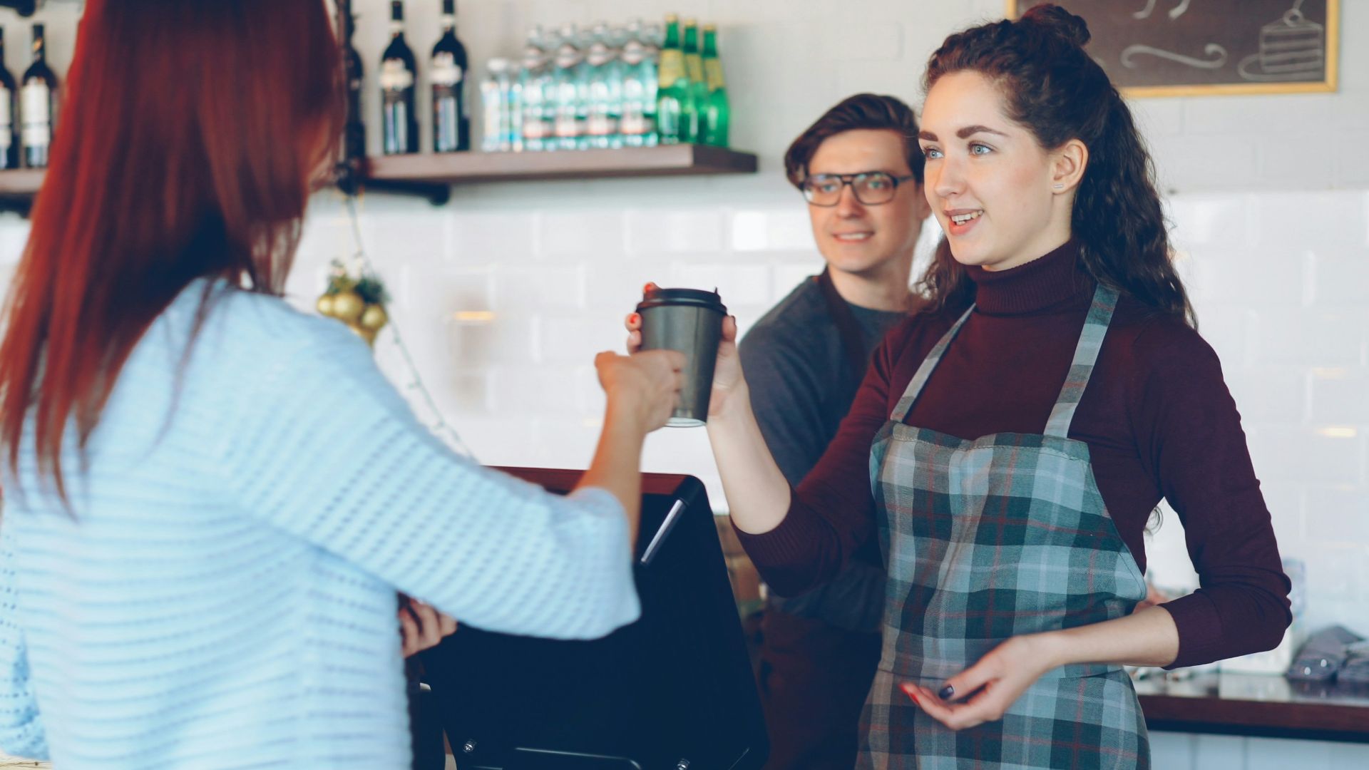 A barista handing coffee to a customer at the counter.
