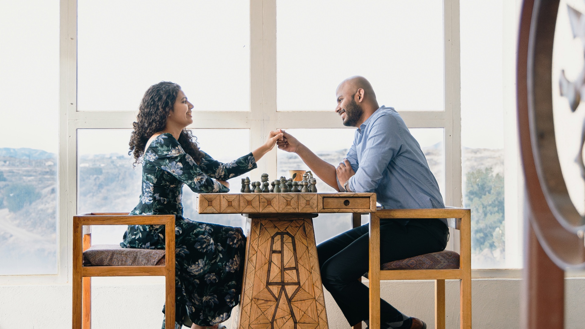 a man and woman sitting at a table playing chess