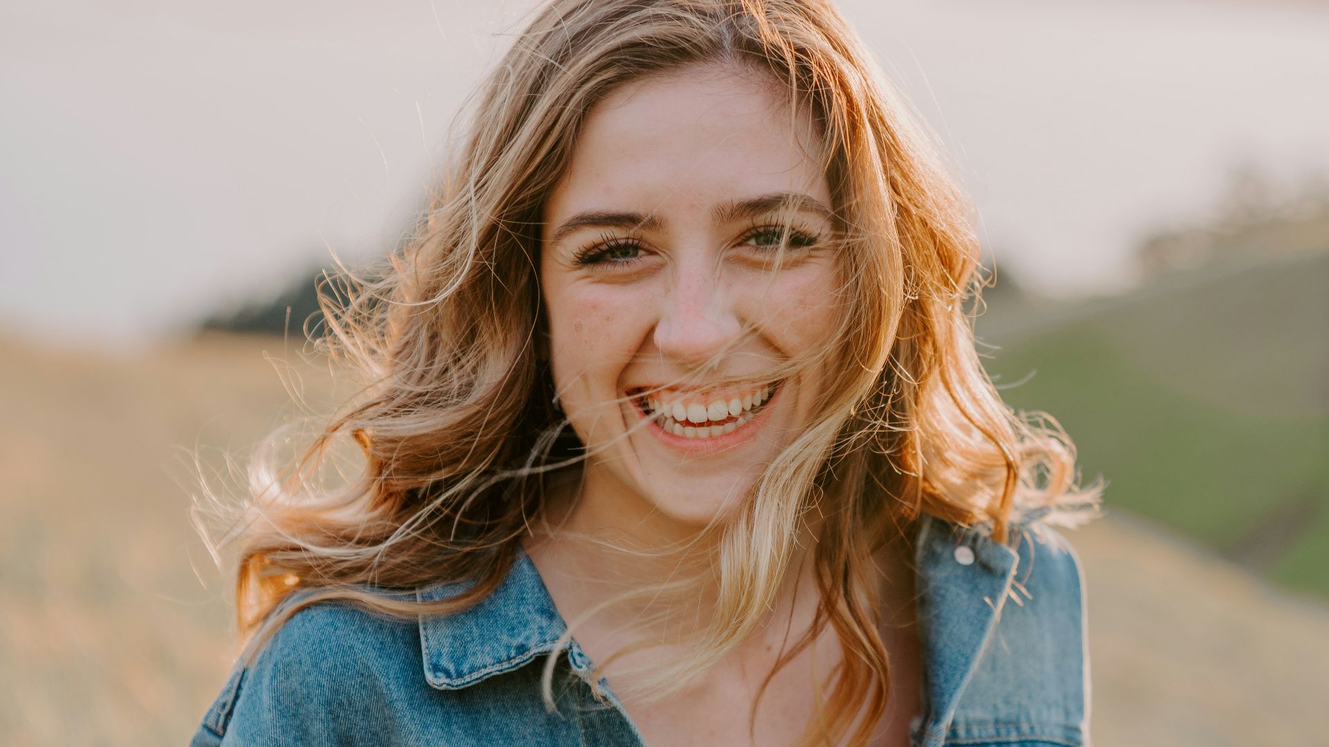 smiling woman sitting on grass during daytime