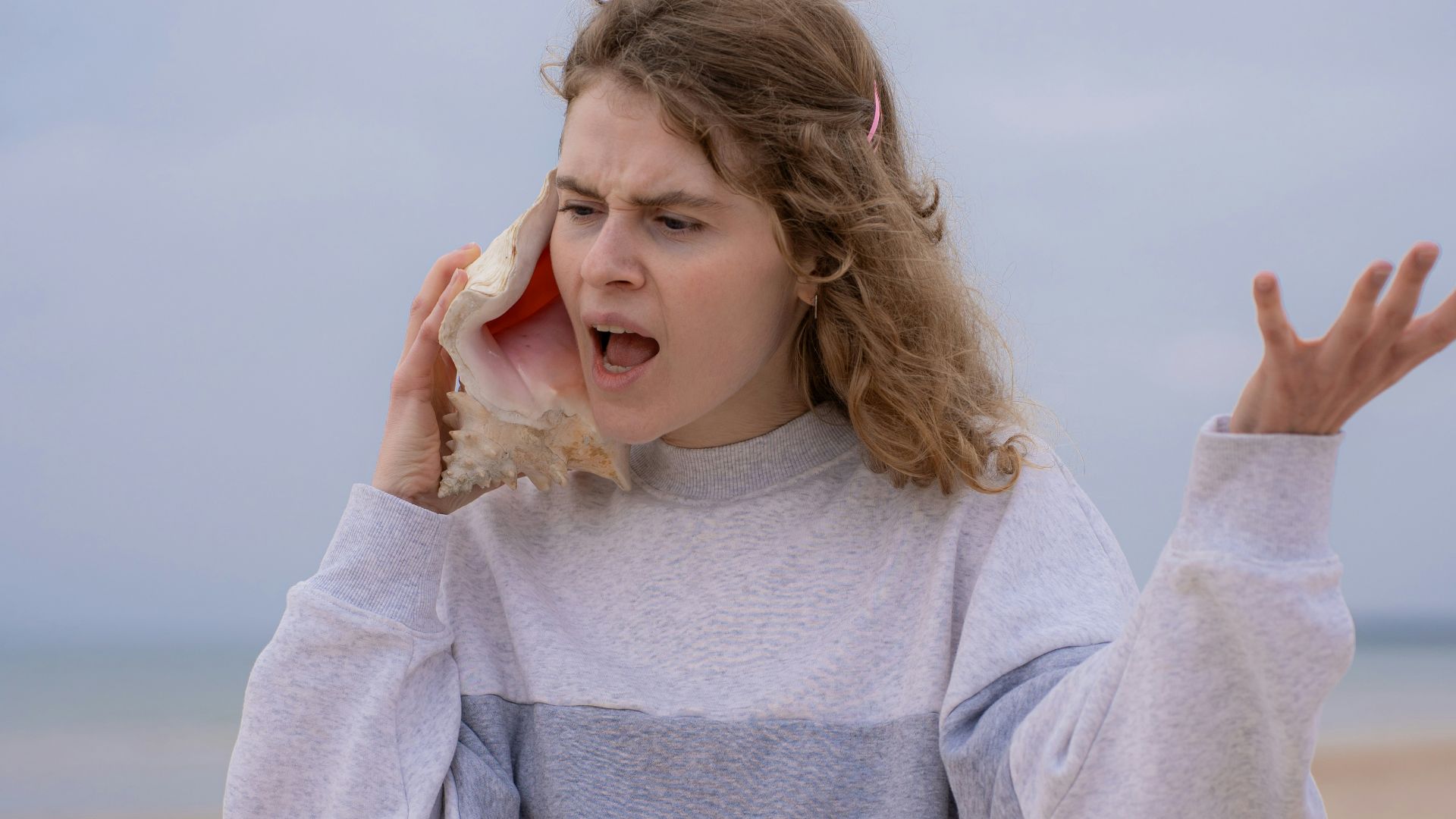 a woman on the beach holding a cell phone to her ear