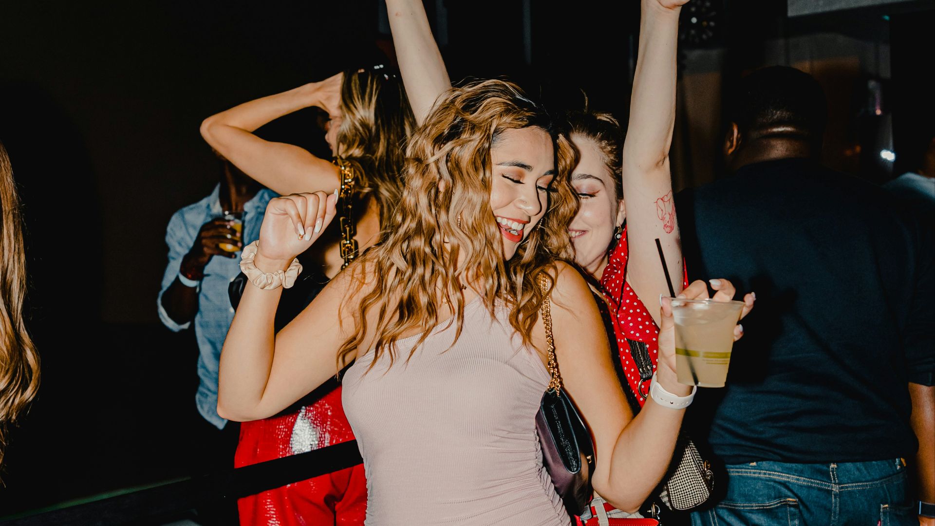 woman in red tank top and blue denim shorts standing beside woman in black tank top