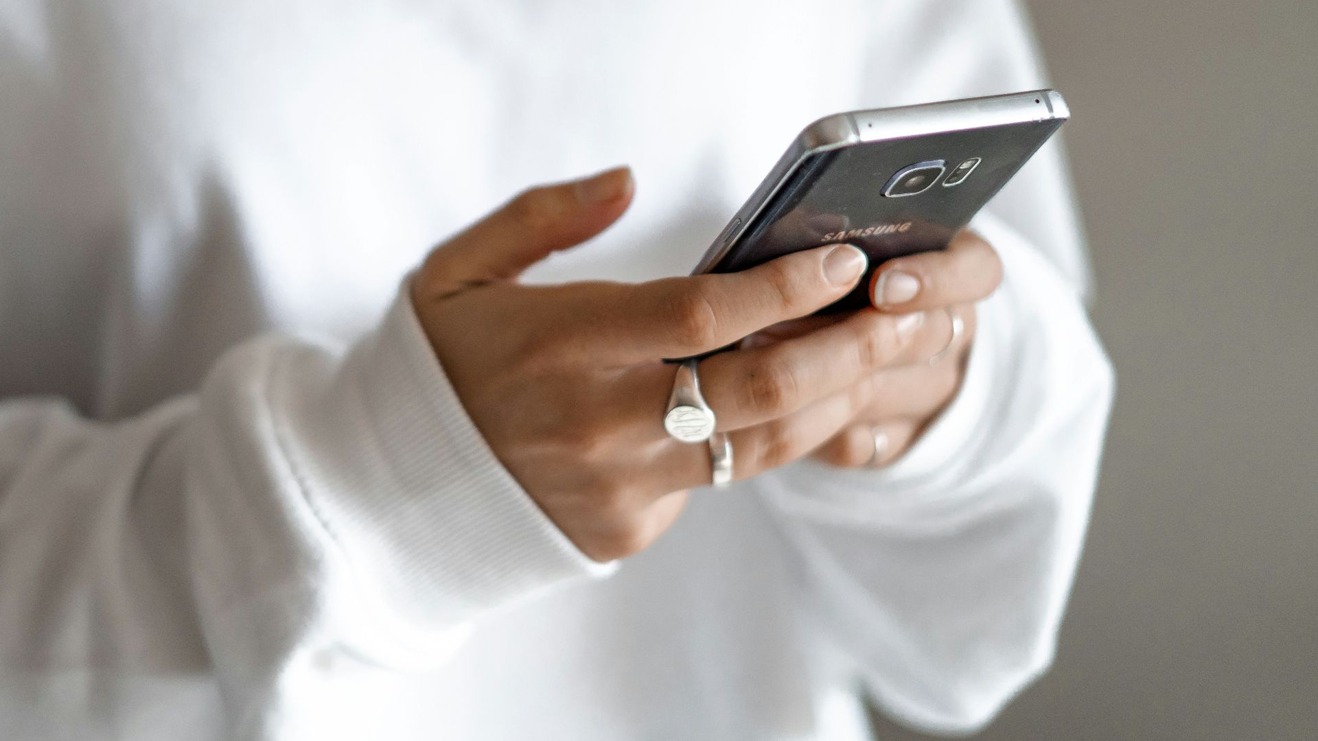 person in white long sleeve shirt holding black smartphone